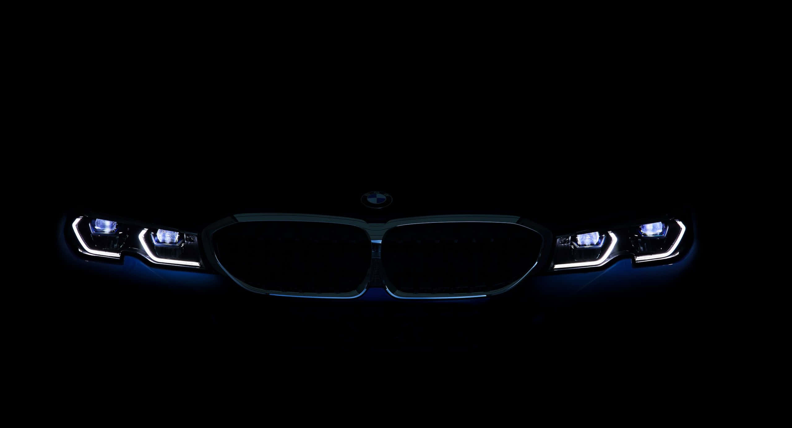 Bmw Tablet 桌布 壁紙 — 一輛BMW汽車的發光頭燈以銳利的藍白色光束刺穿黑暗，背景漆黑一片。