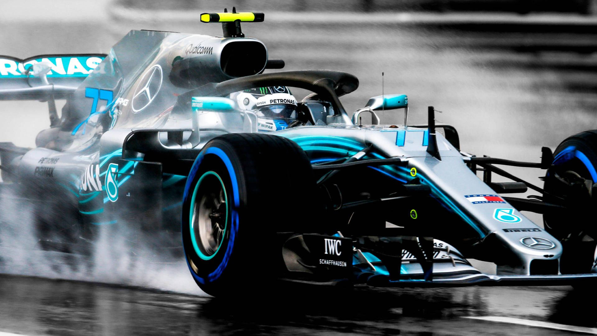 Valtteri Bottas 桌布 壁紙 — 一輛Mercedes一級方程式賽車在濕滑的雨道上飛馳，輪胎噴出水霧，在單色背景下呈現鮮明的藍色點綴。