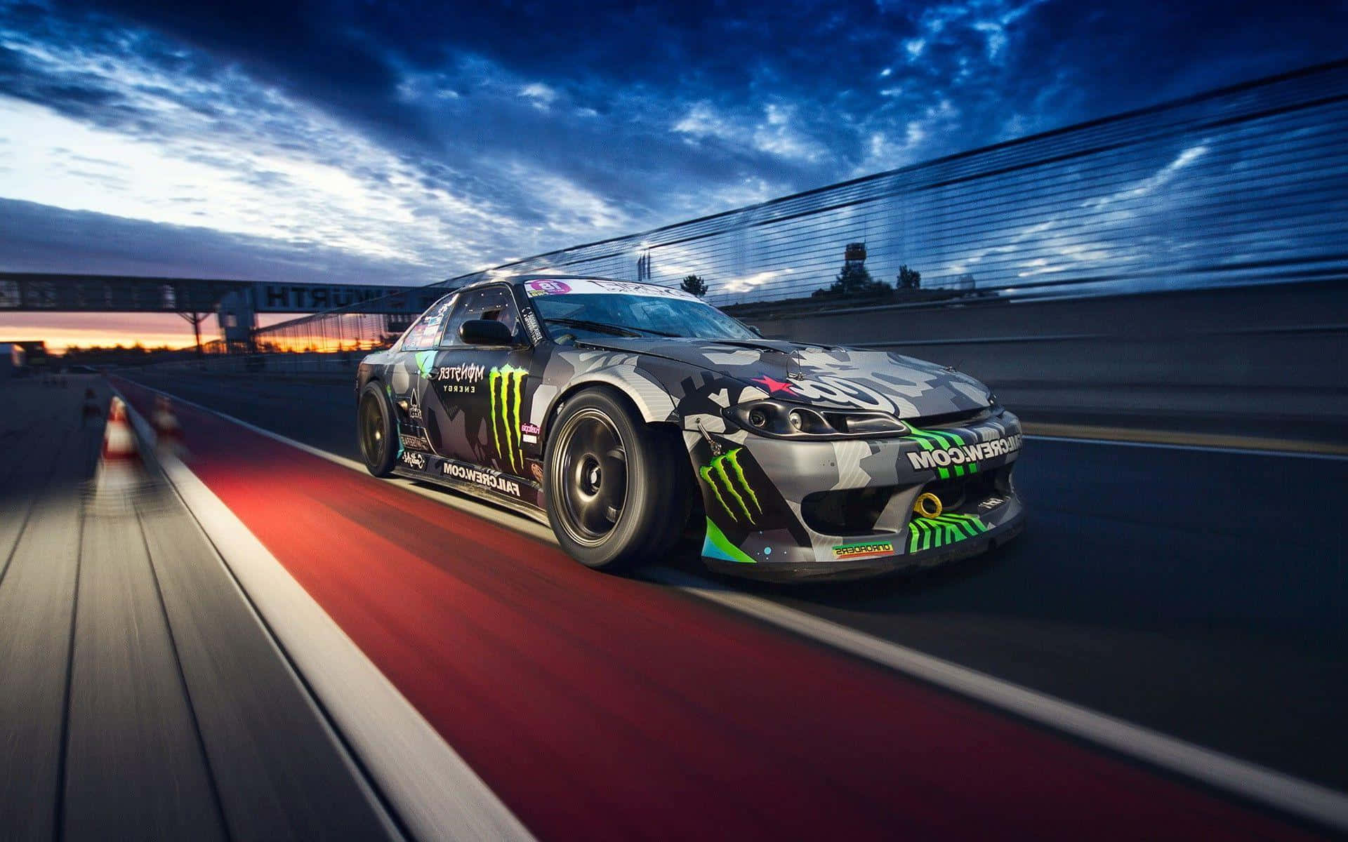 Monster Energy 桌布 壁紙 — 一輛Monster Energy甩尾車在黃昏時分沿著賽道疾馳，帶有動態模糊和戲劇性的天空。