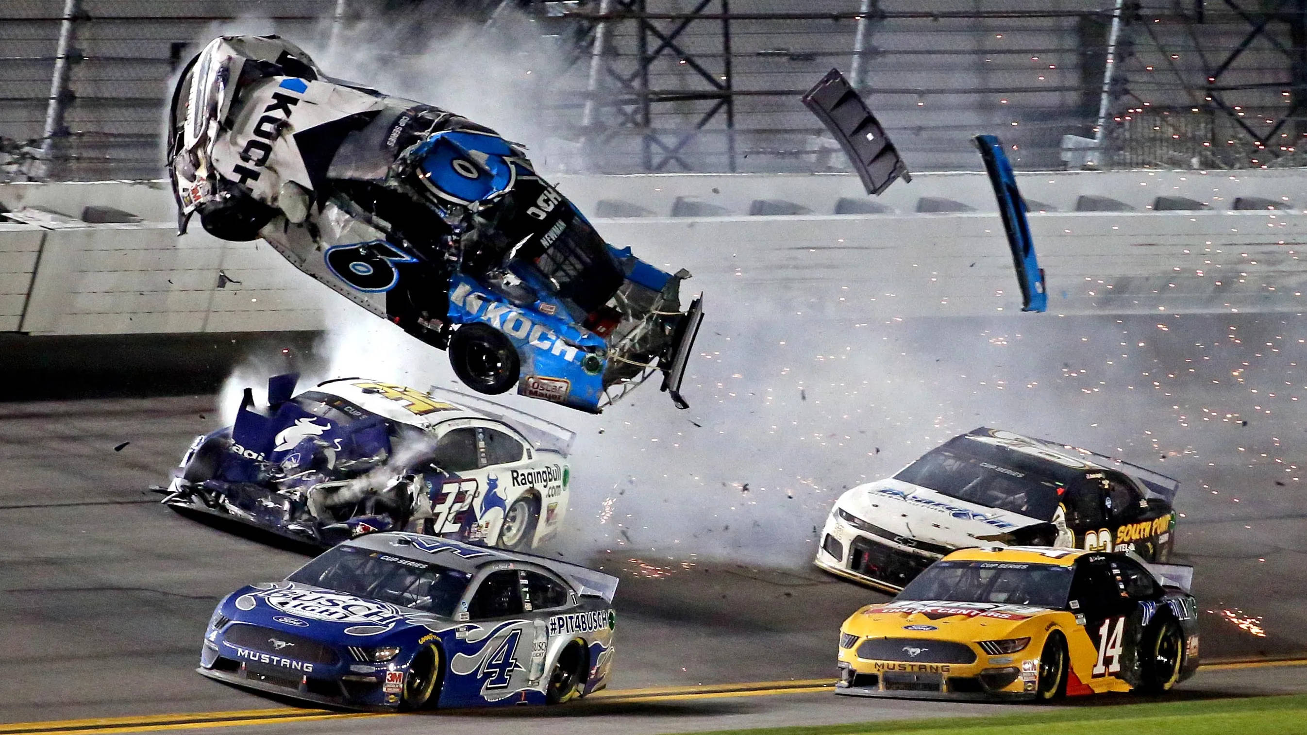 cars 桌布 壁紙 — 一輛NASCAR賽車在空中翻轉，發生猛烈火災撞車，火花和碎片散落在賽道上。