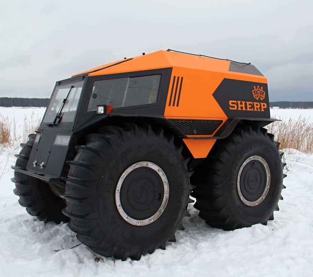 Off-road Car 桌布 壁紙 — 一輛亮橙色和黑色的Sherp全地形車，配備巨大的釘胎，停泊在陰天下的雪地中。