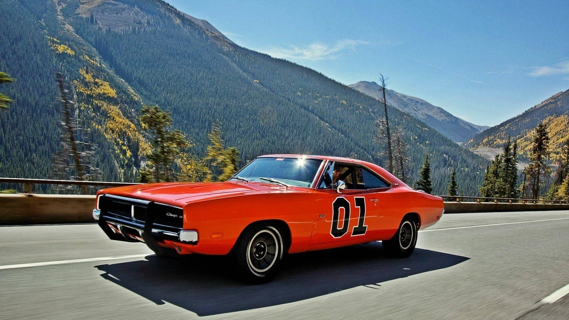 cars 桌布 壁紙 — 一輛亮橙色的1970年道奇Charger，帶有黑色01號碼，在晴朗藍天下沿著山區高速公路奔馳。
