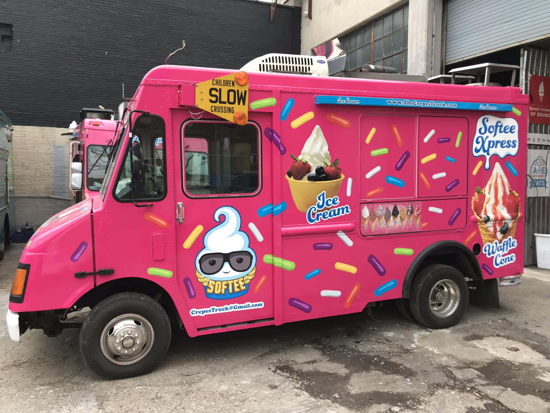 Ice Cream Truck 桌布 壁紙 — 一輛亮粉色的冰淇淋車，車身佈滿彩色糖粒和卡通圖案，停泊在都市小巷中。