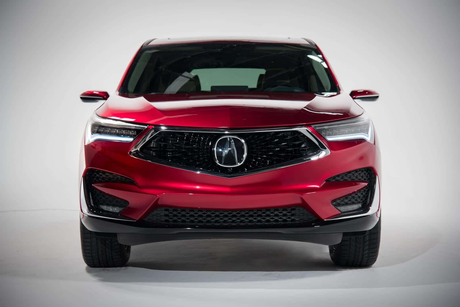 Acura Mdx 桌布 壁紙 — 一輛亮紅色Acura SUV的前視圖，配備銳利頭燈和鍍鉻格柵，背景為純白色攝影棚。