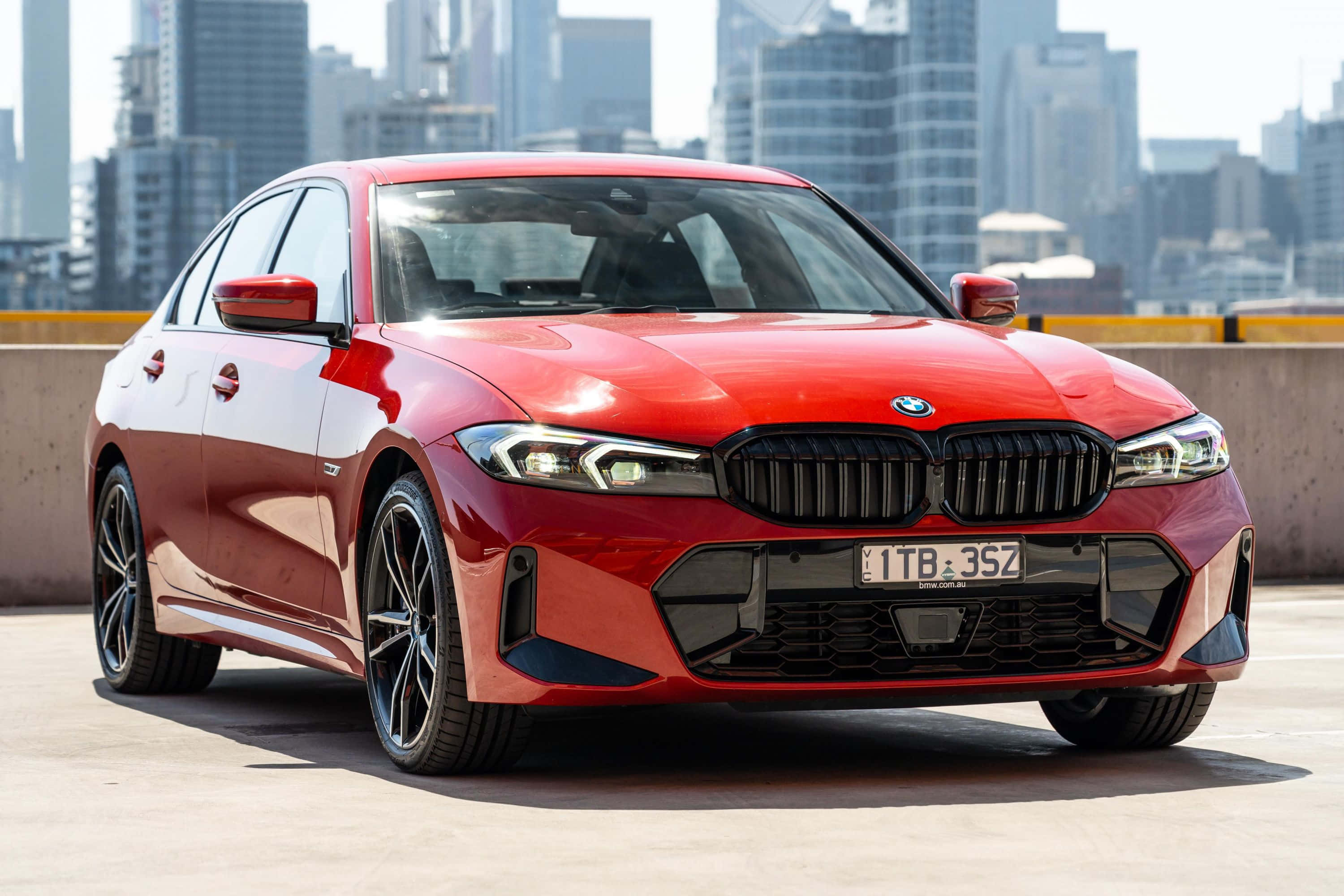 Bmw 3 Series 桌布 壁紙 — 一輛亮紅色BMW 3系列轎車停放在混凝土屋頂上，背景是現代城市天際線。