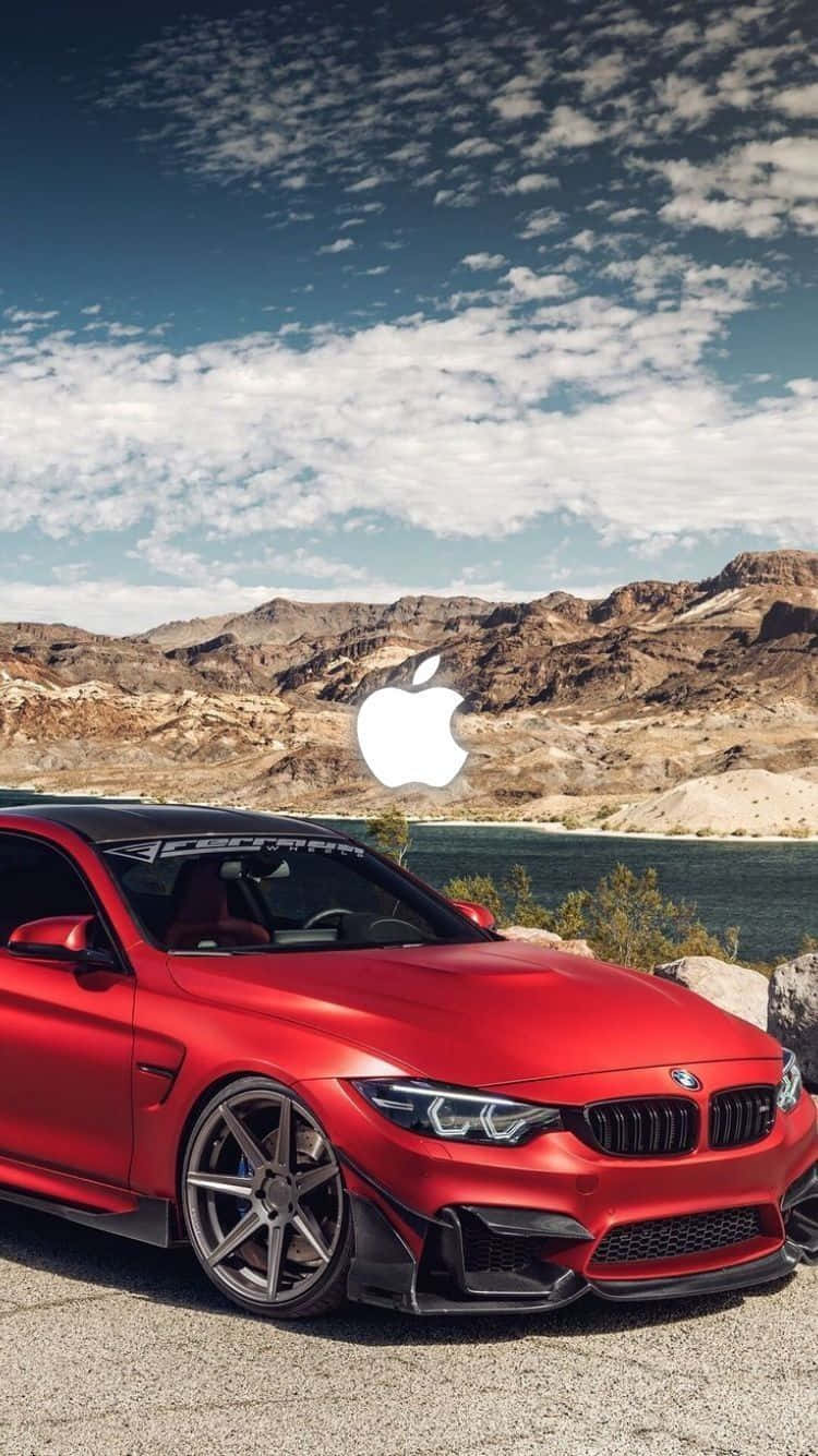 桌布 壁紙 — 一輛亮紅色BMW M4跑車停泊在沙漠湖邊，遠處山脈上疊加了一個巨大的Apple標誌，天空部分多雲。