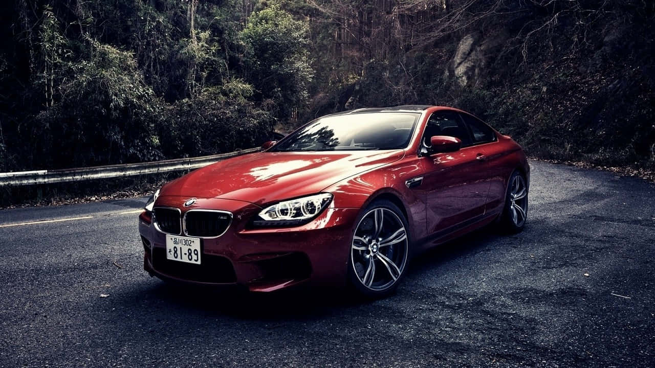 720p Bmw 桌布 壁紙 — 一輛亮紅色BMW M6雙門跑車停泊在蜿蜒的森林道路上，背景有深色樹木和護欄。