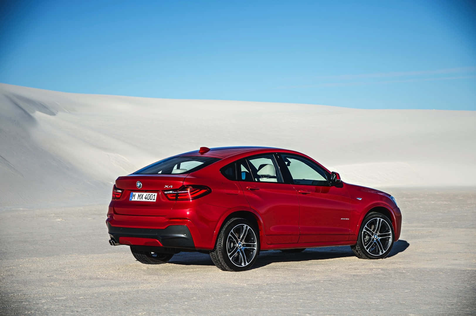 Bmw X4 桌布 壁紙 — 一輛亮紅色BMW X4 SUV停放在廣闊的白色沙丘上，天空清澈湛藍。