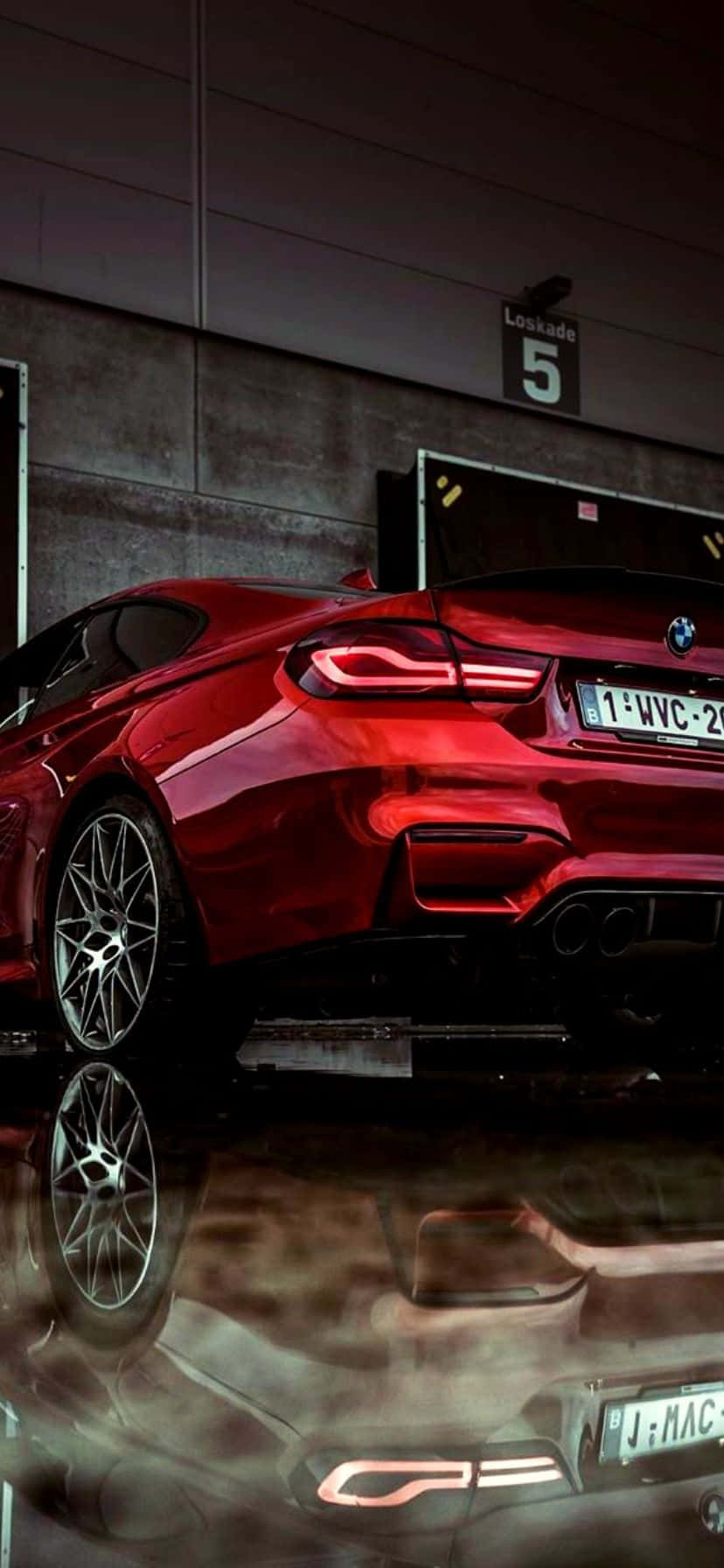 BMW 動圖 桌布 壁紙 — 一輛亮紅色BMW跑車停放在昏暗的車庫中，尾燈發光，在濕漉漉的混凝土上閃爍著倒影。