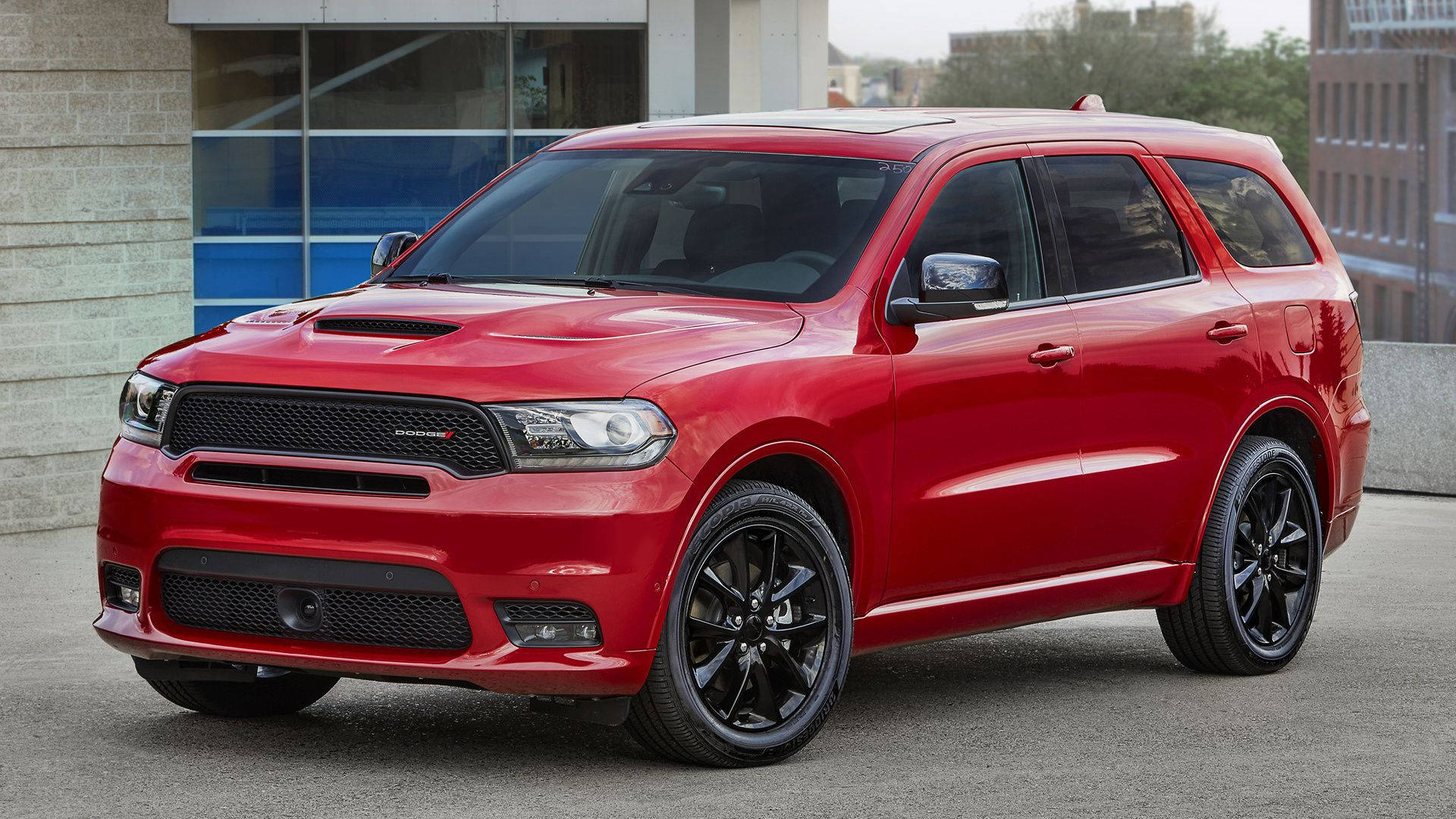 Dodge 桌布 壁紙 — 一輛亮紅色Dodge Durango SRT SUV配黑色輪圈，停泊在現代建築附近的柏油路面上。