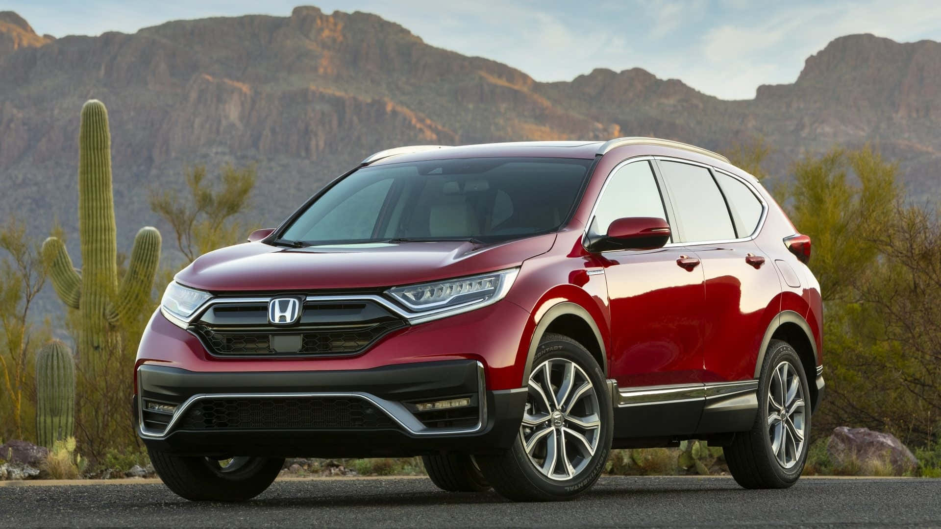 Honda Cr-v 桌布 壁紙 — 一輛亮紅色本田CR-V SUV停泊在沙漠道路上，背景有岩石山脈和薩瓜羅仙人掌。