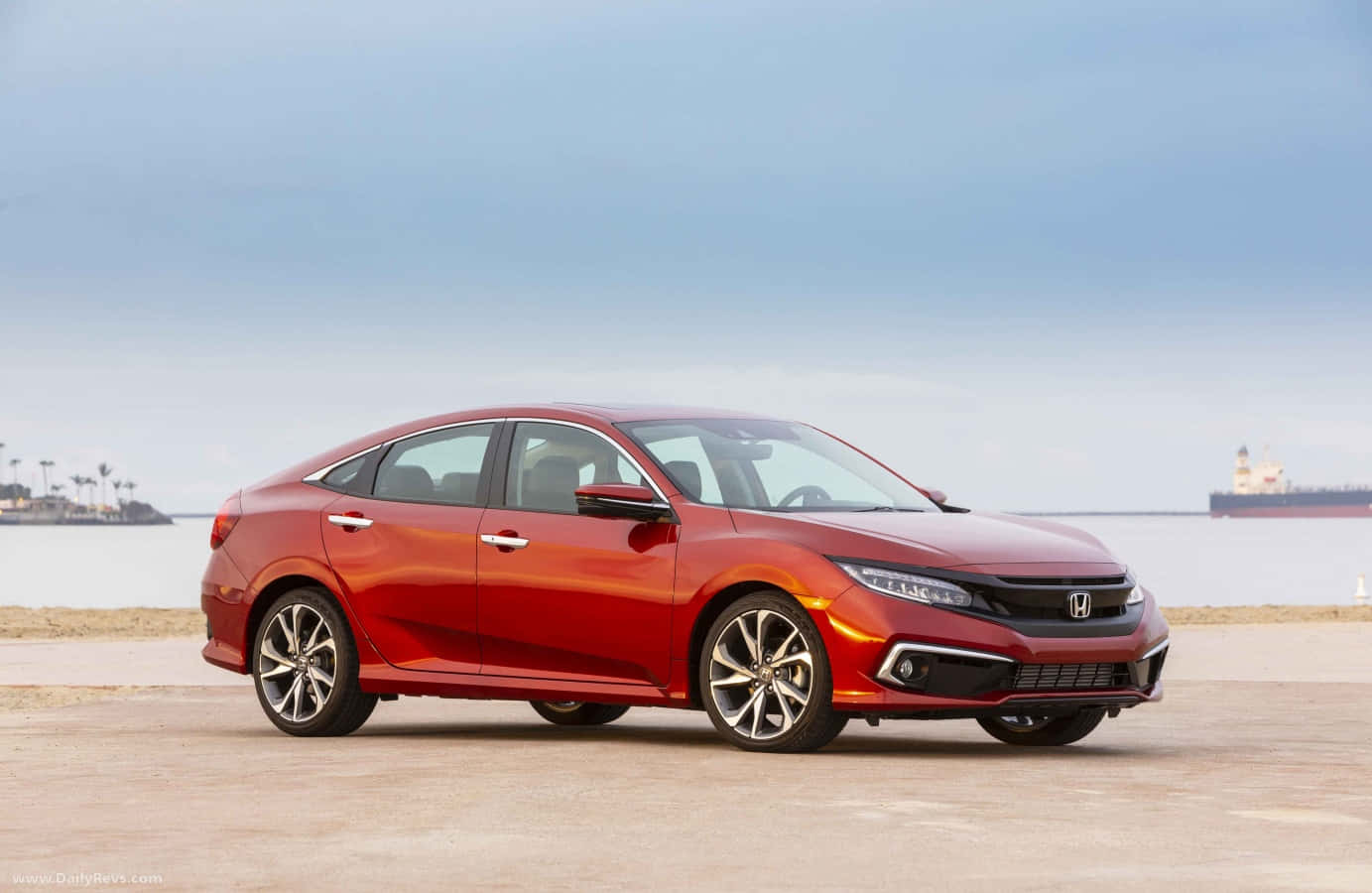 Honda Civic 桌布 壁紙 — 一輛亮紅色本田思域轎車停在混凝土碼頭上，平靜的海洋和遠處的貨船在清澈的藍天下。