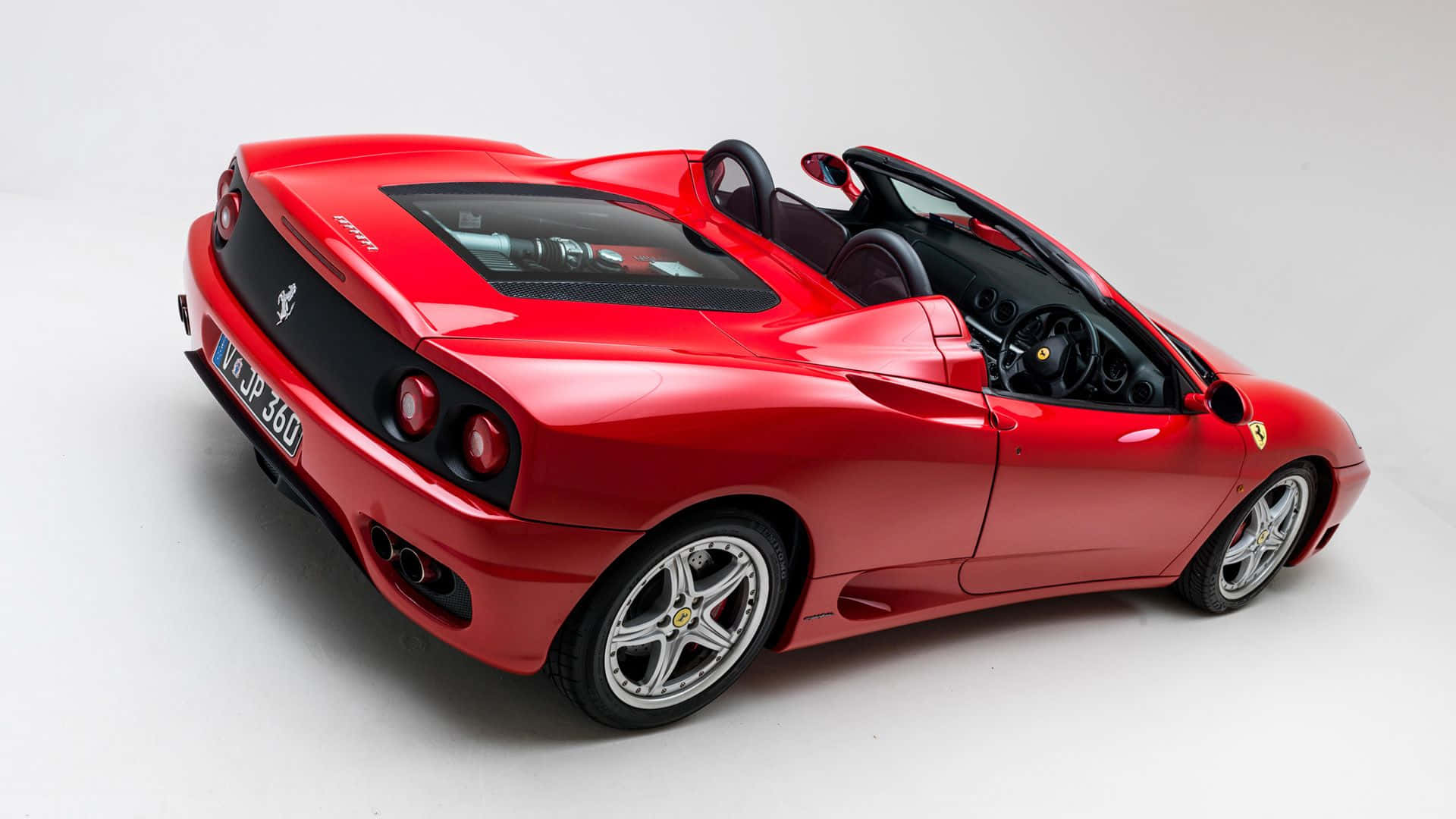 Ferrari 360 Modena 桌布 壁紙 — 一輛亮紅色法拉利360 Spider敞篷跑車，車頂敞開，在純白工作室背景襯托下展示其流暢曲線和黑色內裝。