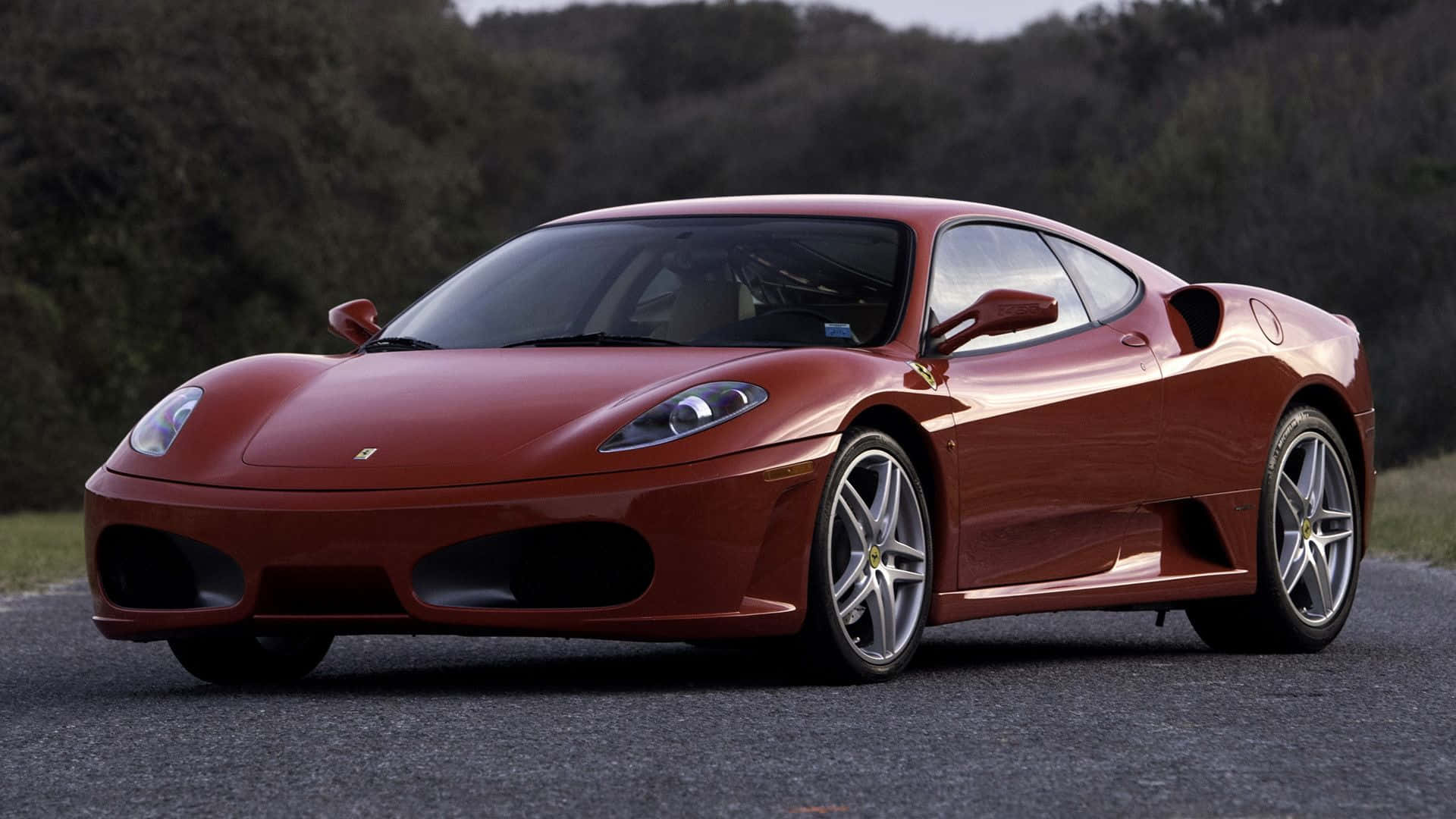 Ferrari F430 桌布 壁紙 — 一輛亮紅色法拉利360跑車停放在鋪砌道路上，背景有模糊的綠色樹木。