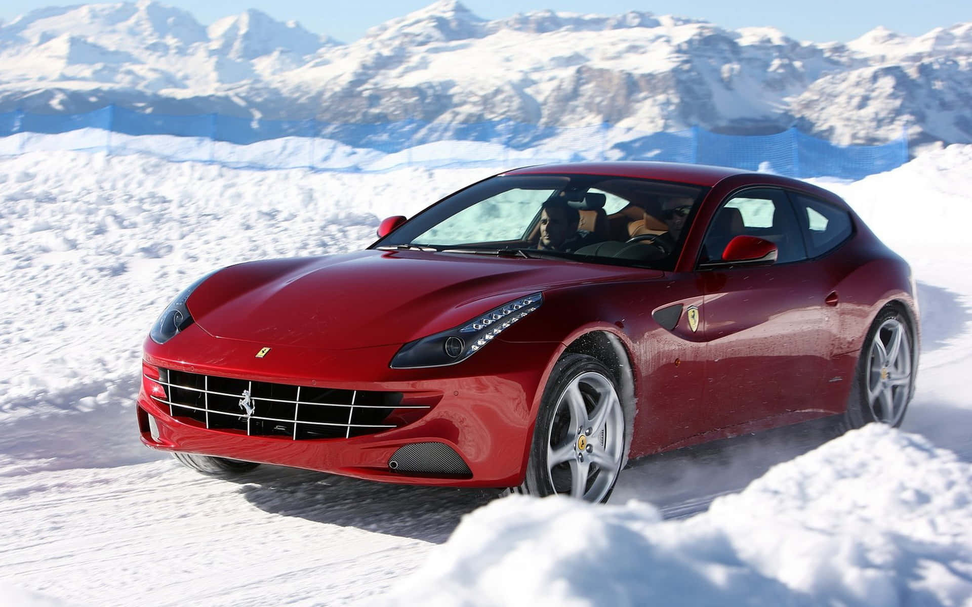 Ferrari Ff 桌布 壁紙 — 一輛亮紅色法拉利跑車在深雪中行駛，背景是白雪覆蓋的山脈。
