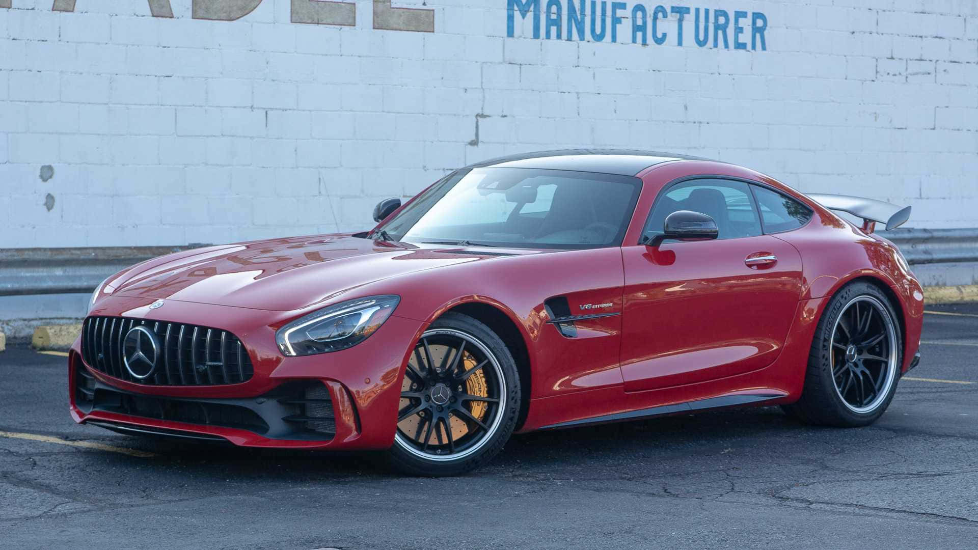 汽車 桌布 壁紙 — 一輛亮紅色的 Mercedes-AMG GT R 跑車停放在白色磚牆前，牆上有褪色的藍色字樣。
