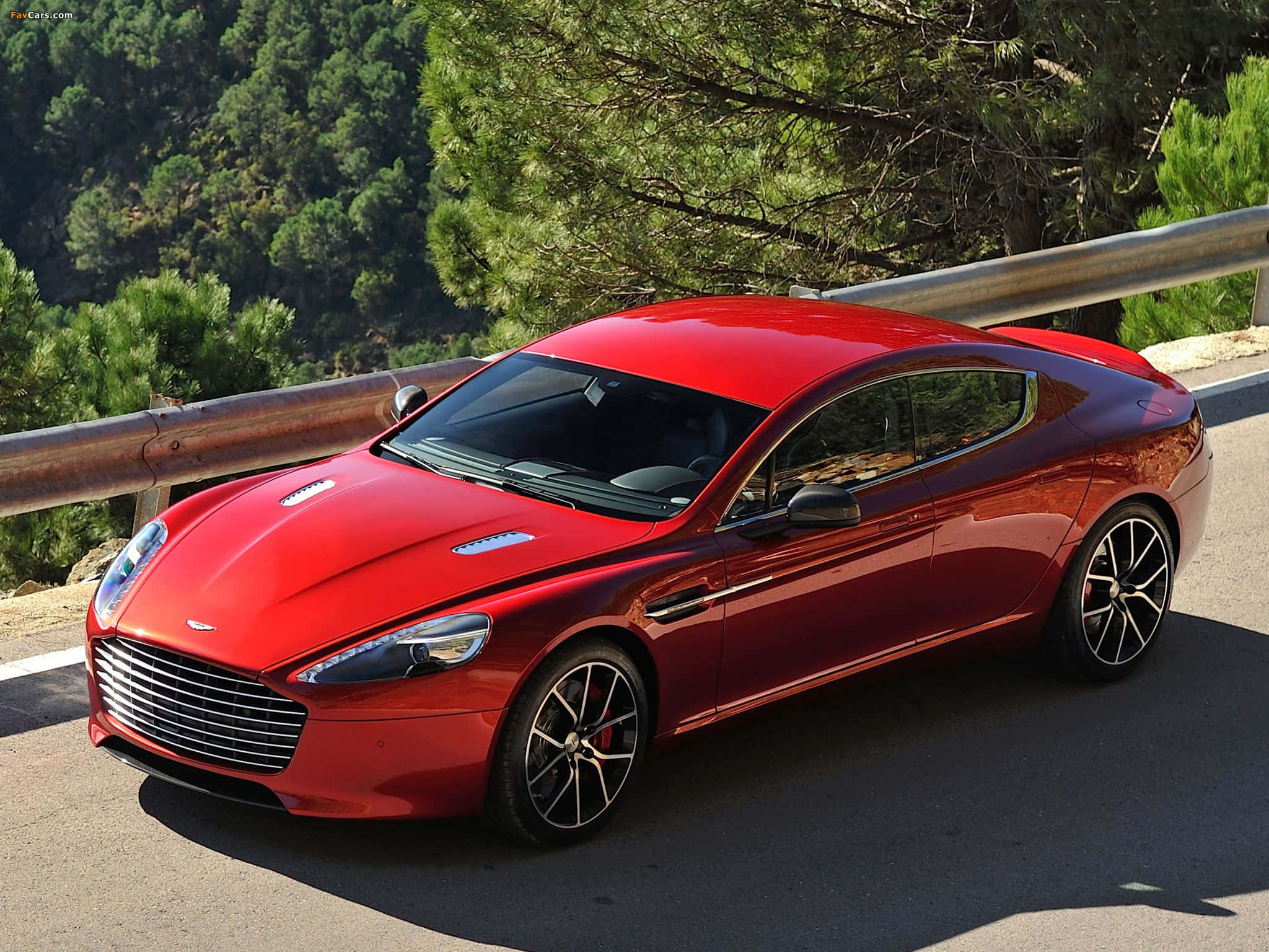Aston Martin Rapide S 桌布 壁紙 — 一輛亮紅色的Aston Martin跑車停放在蜿蜒的山路上，周圍有茂密的綠樹和金屬護欄。