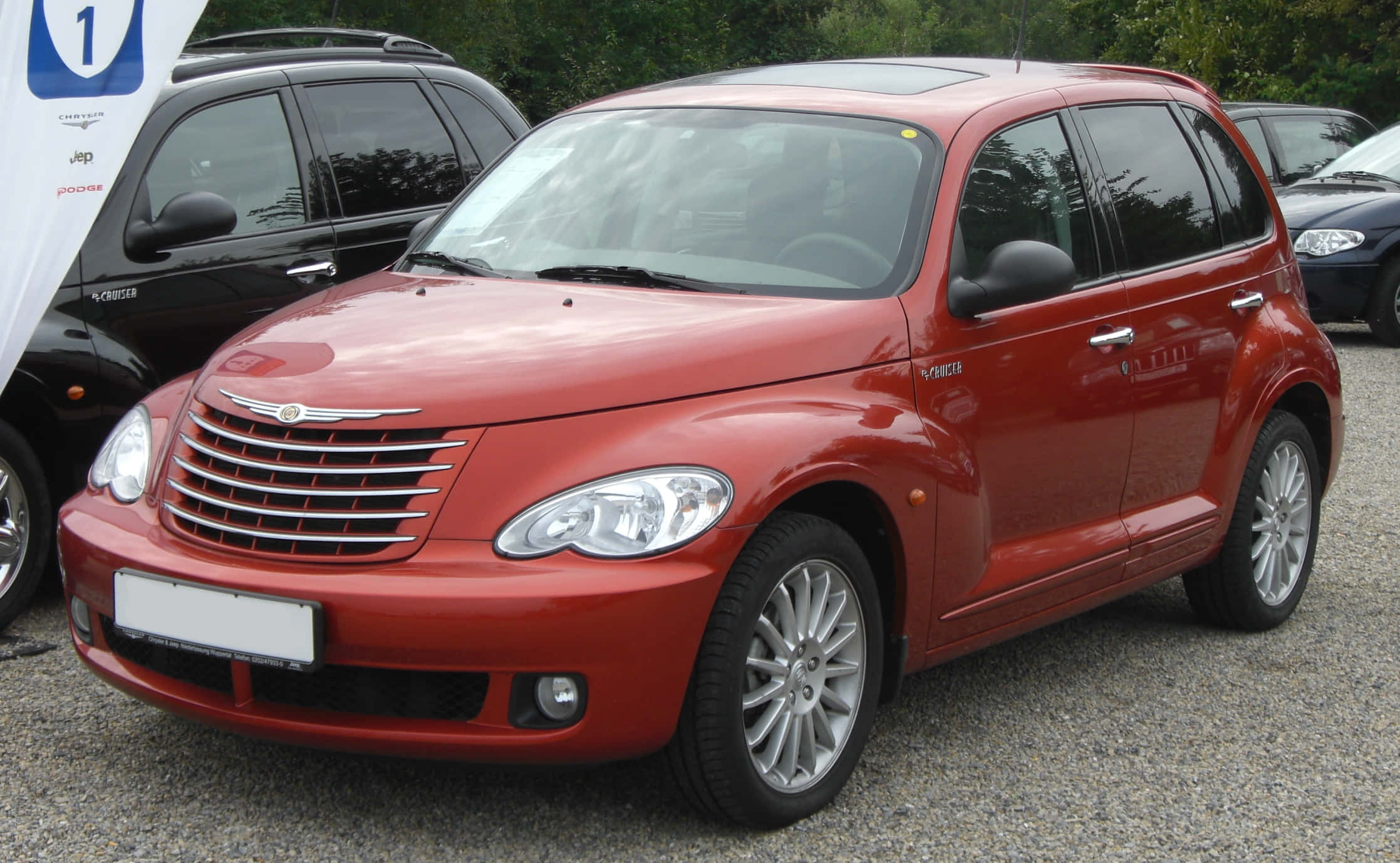 Chrysler Pt Cruiser 桌布 壁紙 — 一輛亮紅色的Chrysler PT Cruiser停在碎石上，背景有樹木。