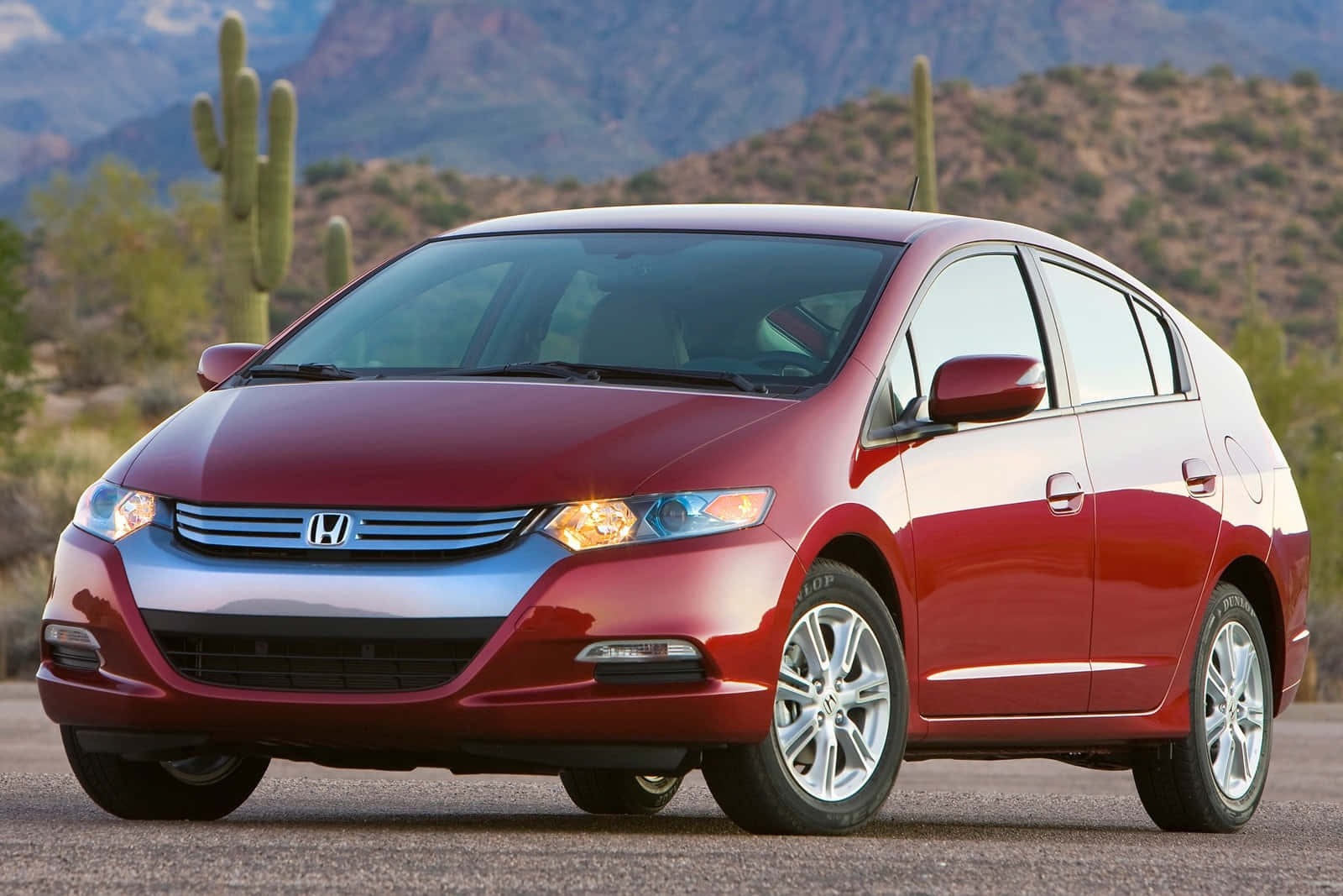 Honda Insight 桌布 壁紙 — 一輛亮紅色的本田Insight混合動力車停在沙漠地面上，背景有薩瓜羅仙人掌和岩石山脈。