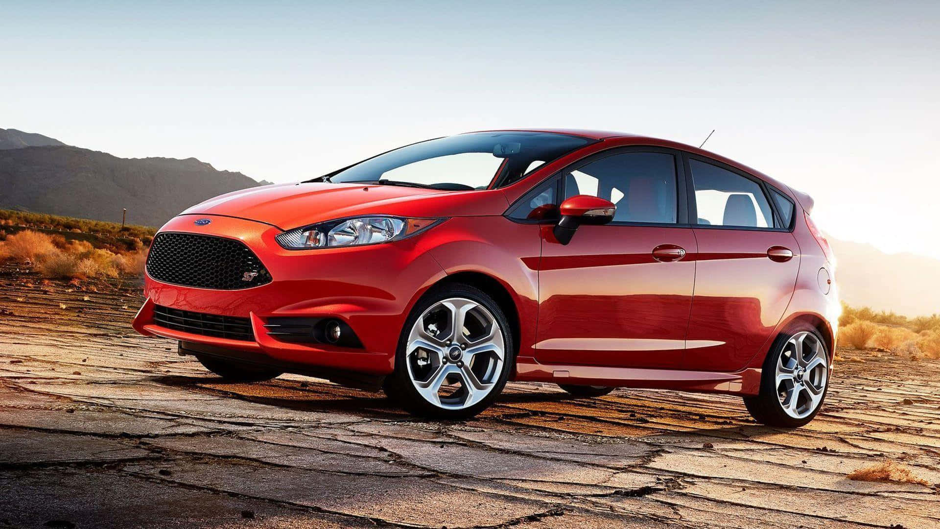 Ford Fiesta 桌布 壁紙 — 一輛亮紅色的福特 Fiesta ST 停泊在龜裂的沙漠路面上，背景是晴朗天空下的山脈。