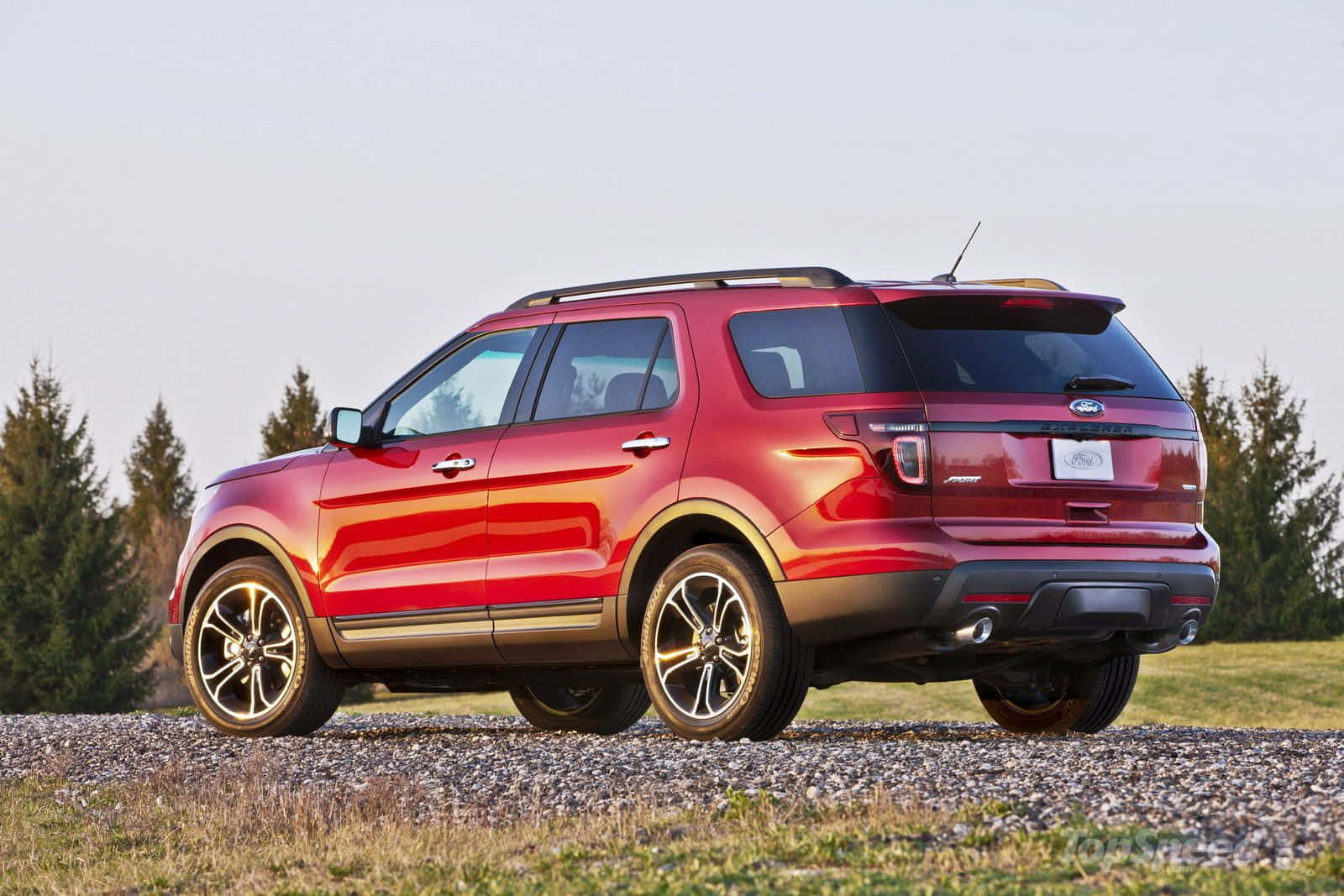 Ford Explorer 桌布 壁紙 — 一輛亮紅色的福特探險者SUV停在碎石上，背景是常綠樹，天空晴朗。