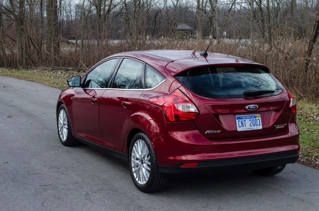 Ford Focus 桌布 壁紙 — 一輛亮紅色的福特福克斯掀背車停在安靜的瀝青路上，旁邊是光禿禿的冬季樹木。