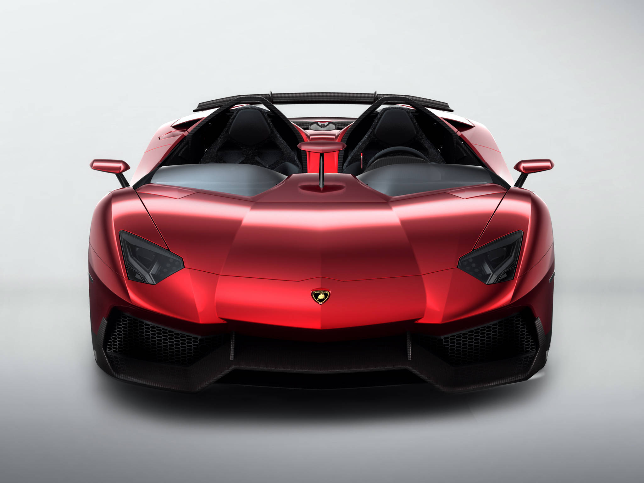 4K 藍寶堅尼 桌布 壁紙 — 一輛亮紅色的藍寶堅尼 Aventador Roadster 正面朝前，帶有侵略性的稜角線條和黑色飾件，背景是簡約的工作室風格。