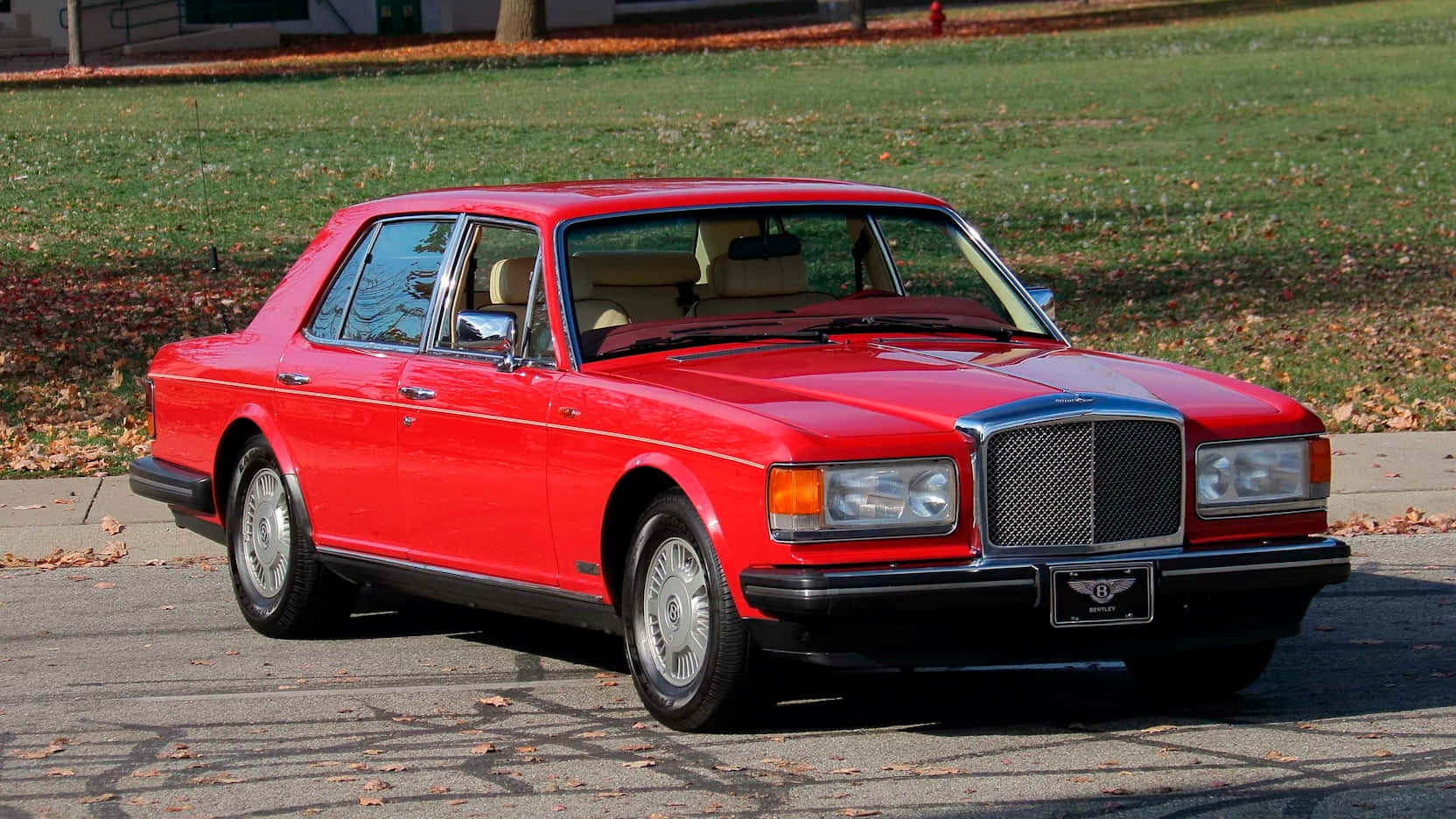 Bentley Eight 桌布 壁紙 — 一輛亮紅色的賓利轎車停在鋪滿落葉的車道上，背景有秋天的草和樹木。