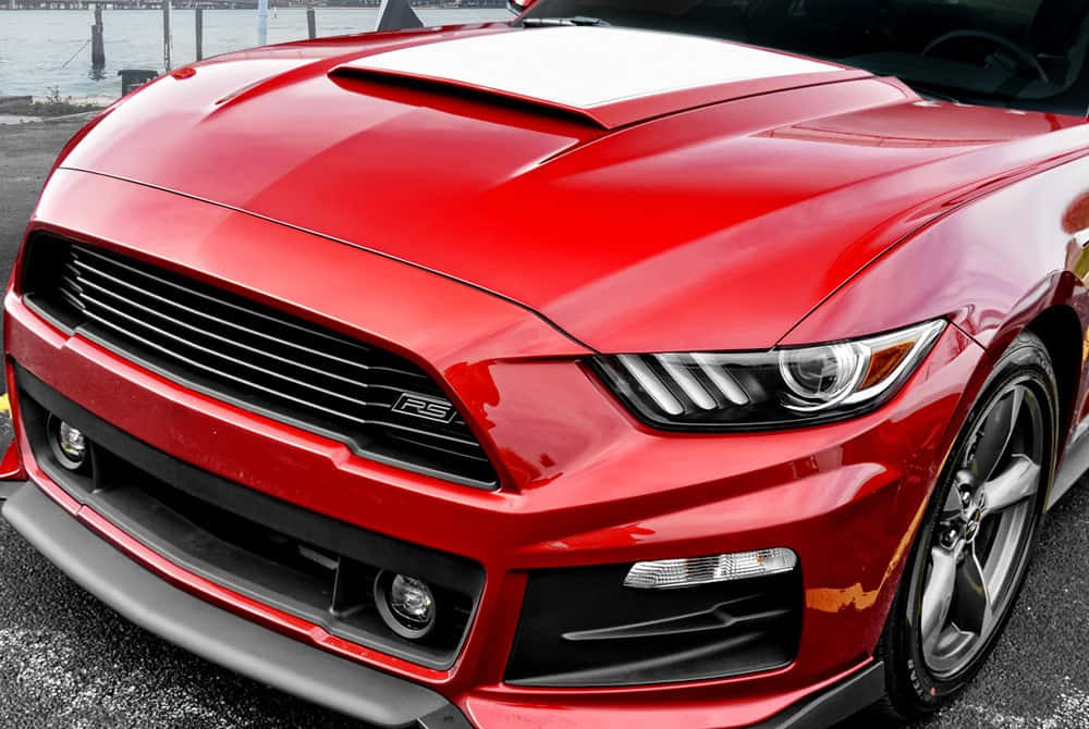 Car Hood 桌布 壁紙 — 一輛亮紅色福特Mustang RS跑車，帶有黑色飾邊和時尚車頭燈，停在水邊。