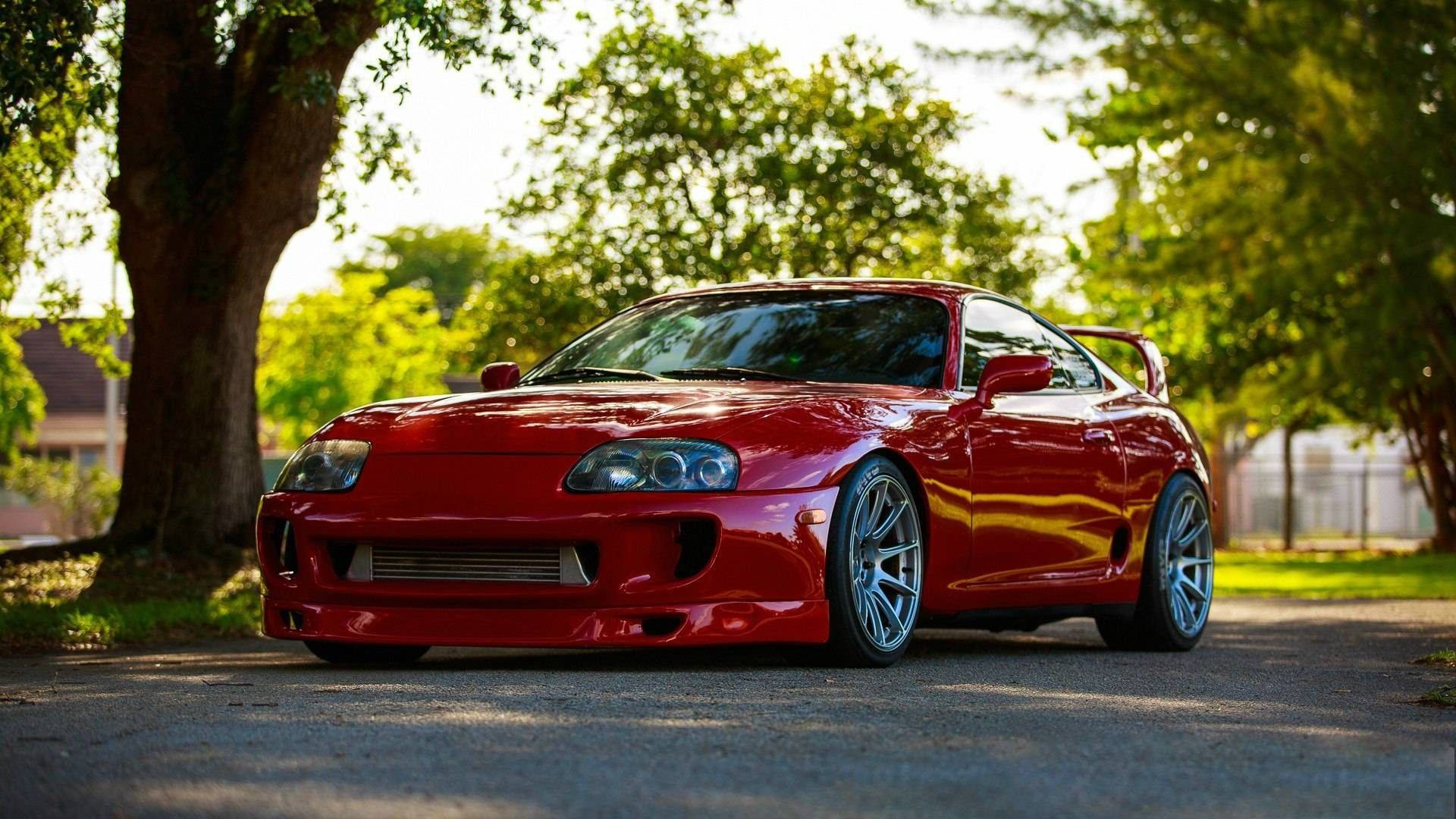 紅色豐田Supra在陽光下停泊在樹下。 — Toyota Supra Mk4 壁紙
