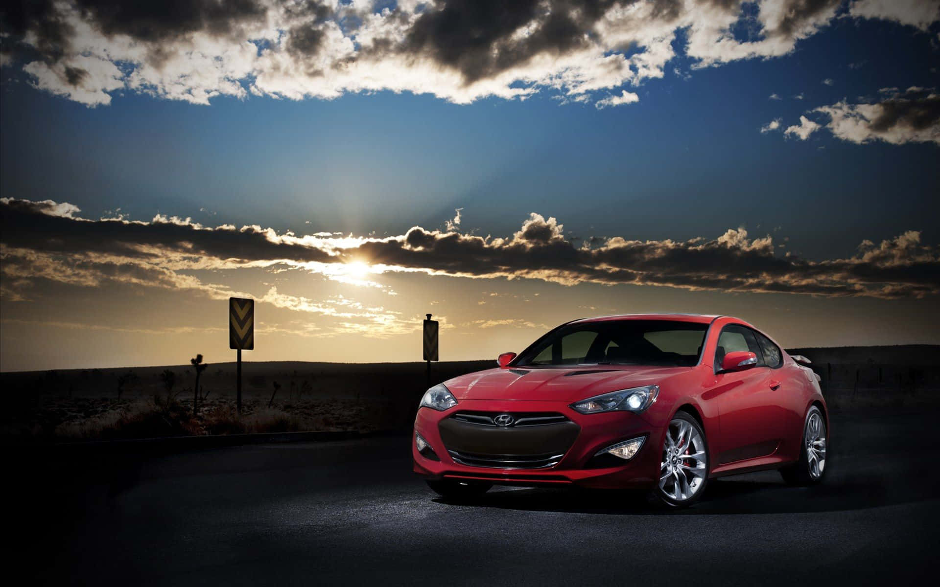 Hyundai Genesis 桌布 壁紙 — 一輛亮紅色跑車停在沙漠公路上，背景是帶有雲彩的戲劇性日落天空。
