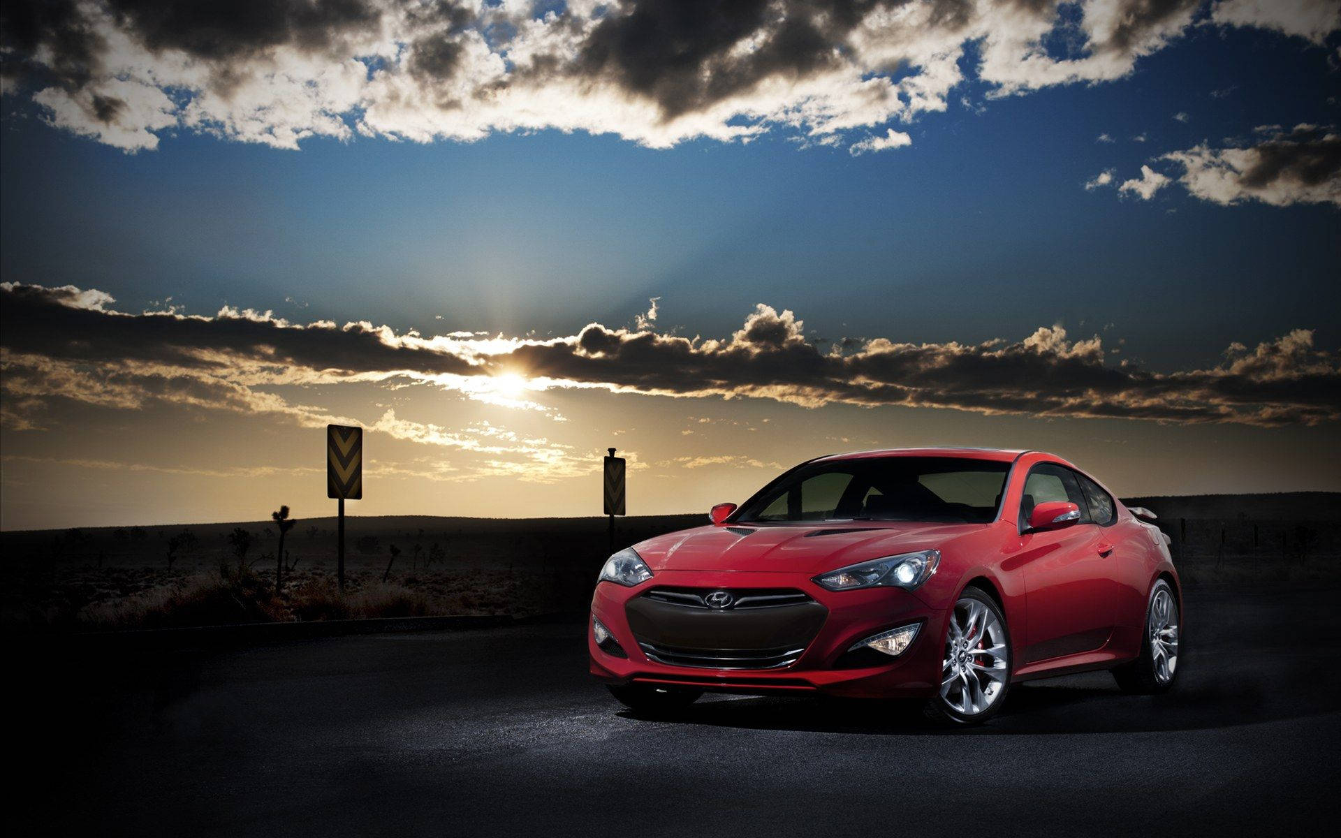 Hyundai 桌布 壁紙 — 一輛亮紅色跑車停在沙漠公路上，背景是壯麗的日落天空，金色雲彩。