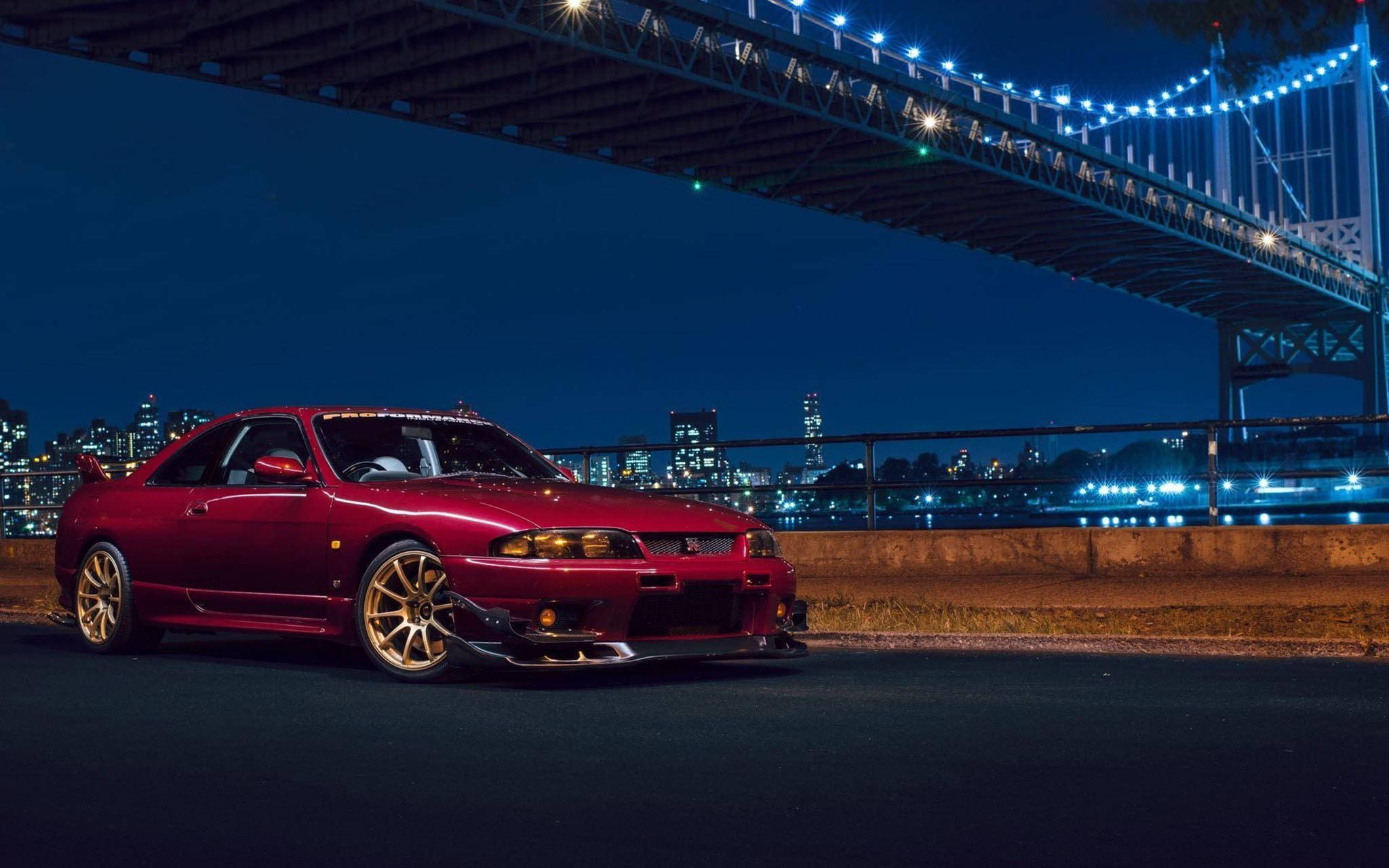 Gtr 桌布 壁紙 — 一輛亮紅色跑車在夜間停泊在燈光璀璨的橋下，背景中城市燈光閃爍。