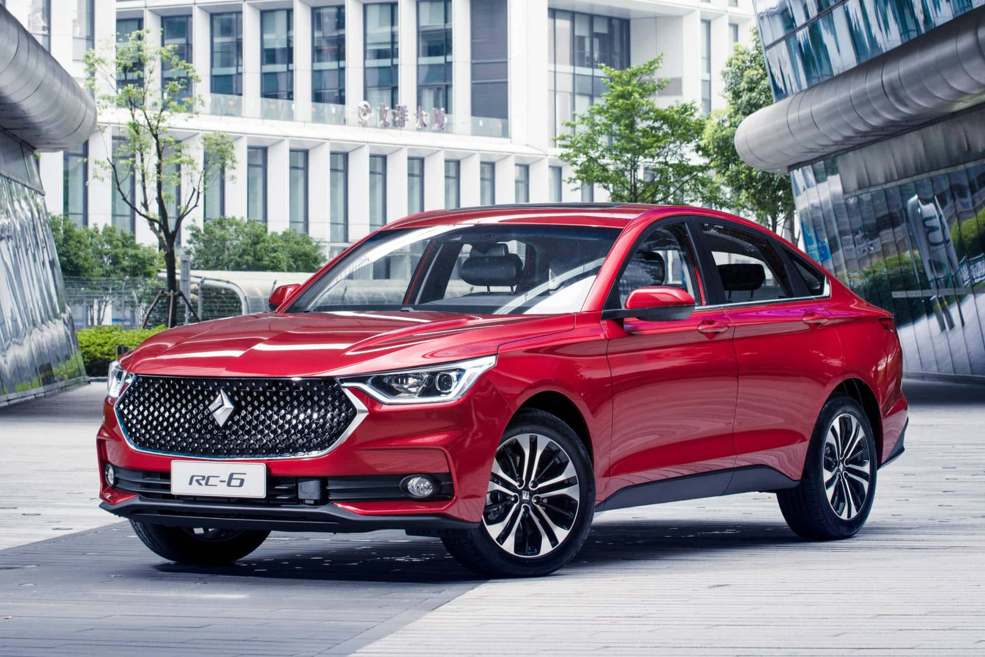 Baojun 桌布 壁紙 — 一輛亮紅色轎車停放在現代都市廣場上，背景有玻璃建築和綠樹。