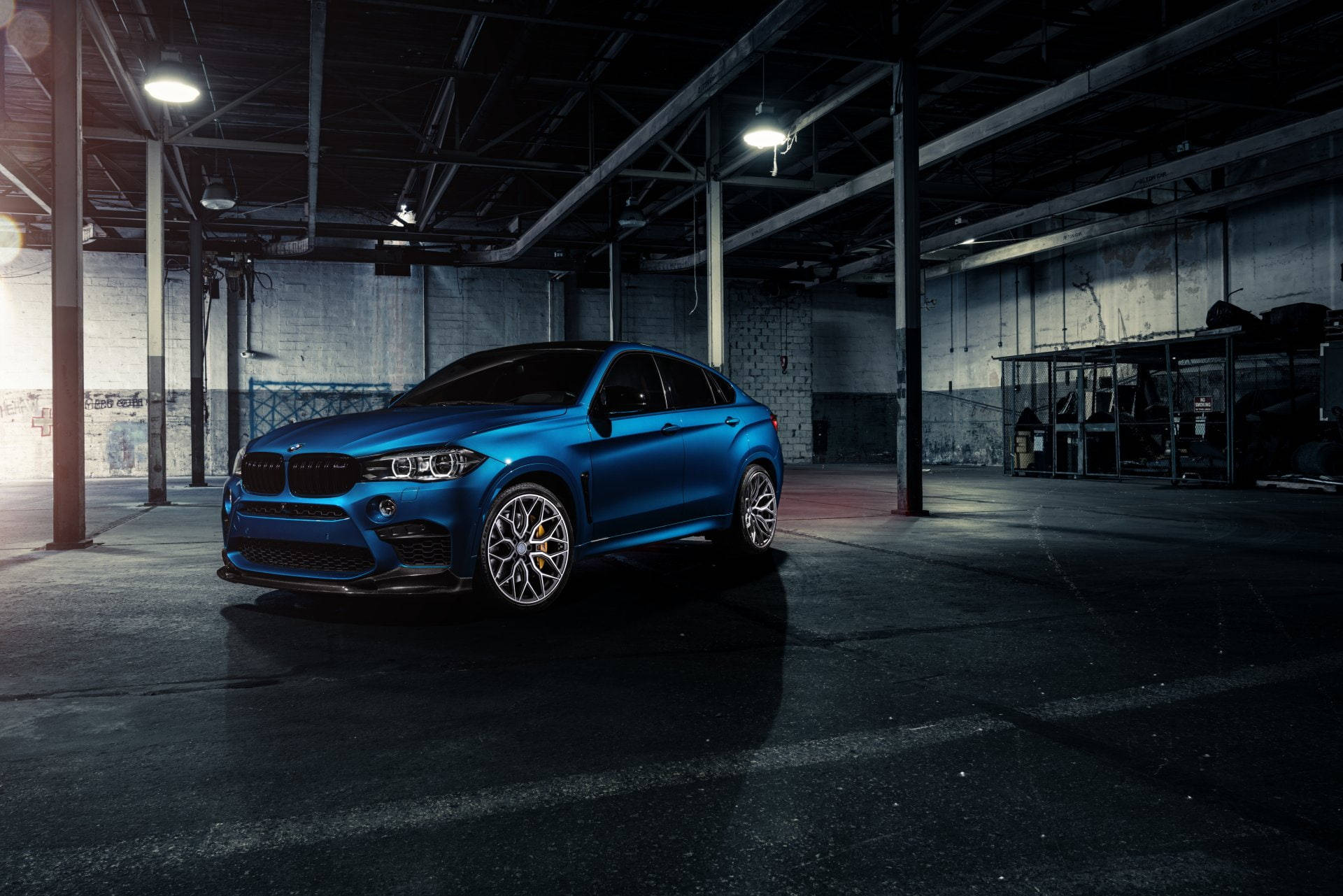 m 桌布 壁紙 — 一輛亮藍色BMW X6 M停放在光線昏暗的工業車庫，車庫有裸露橫樑和混凝土牆。