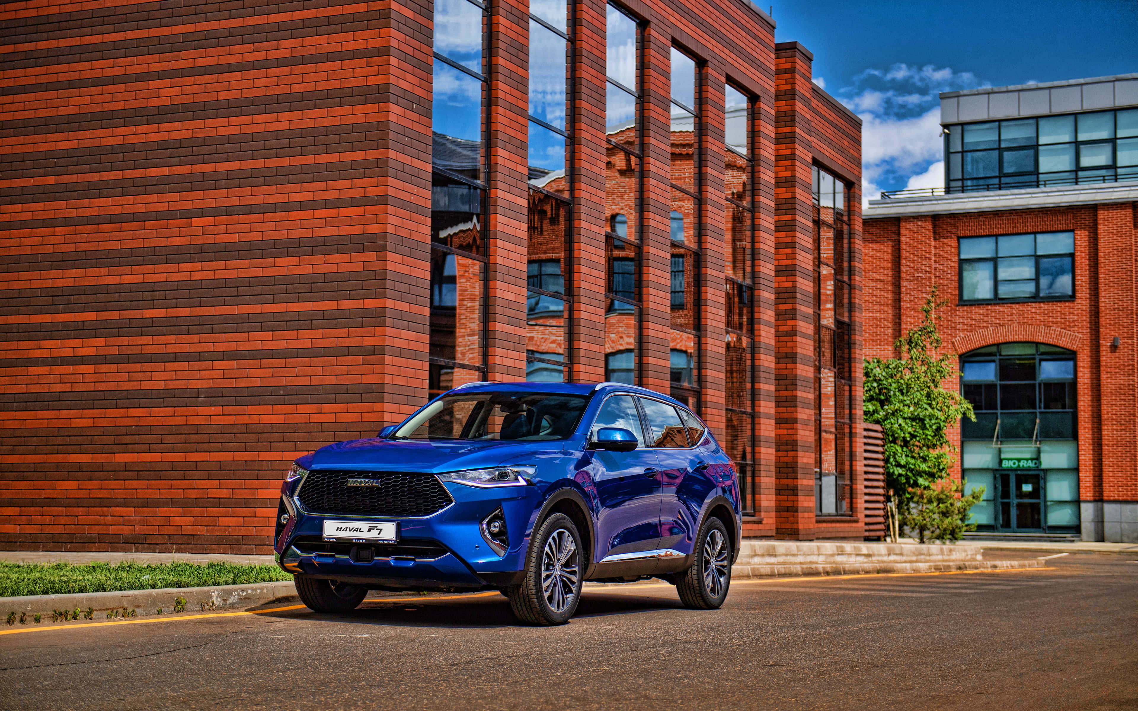 Haval 桌布 壁紙 — 一輛亮藍色SUV停在現代磚砌建築前，天空晴朗蔚藍。