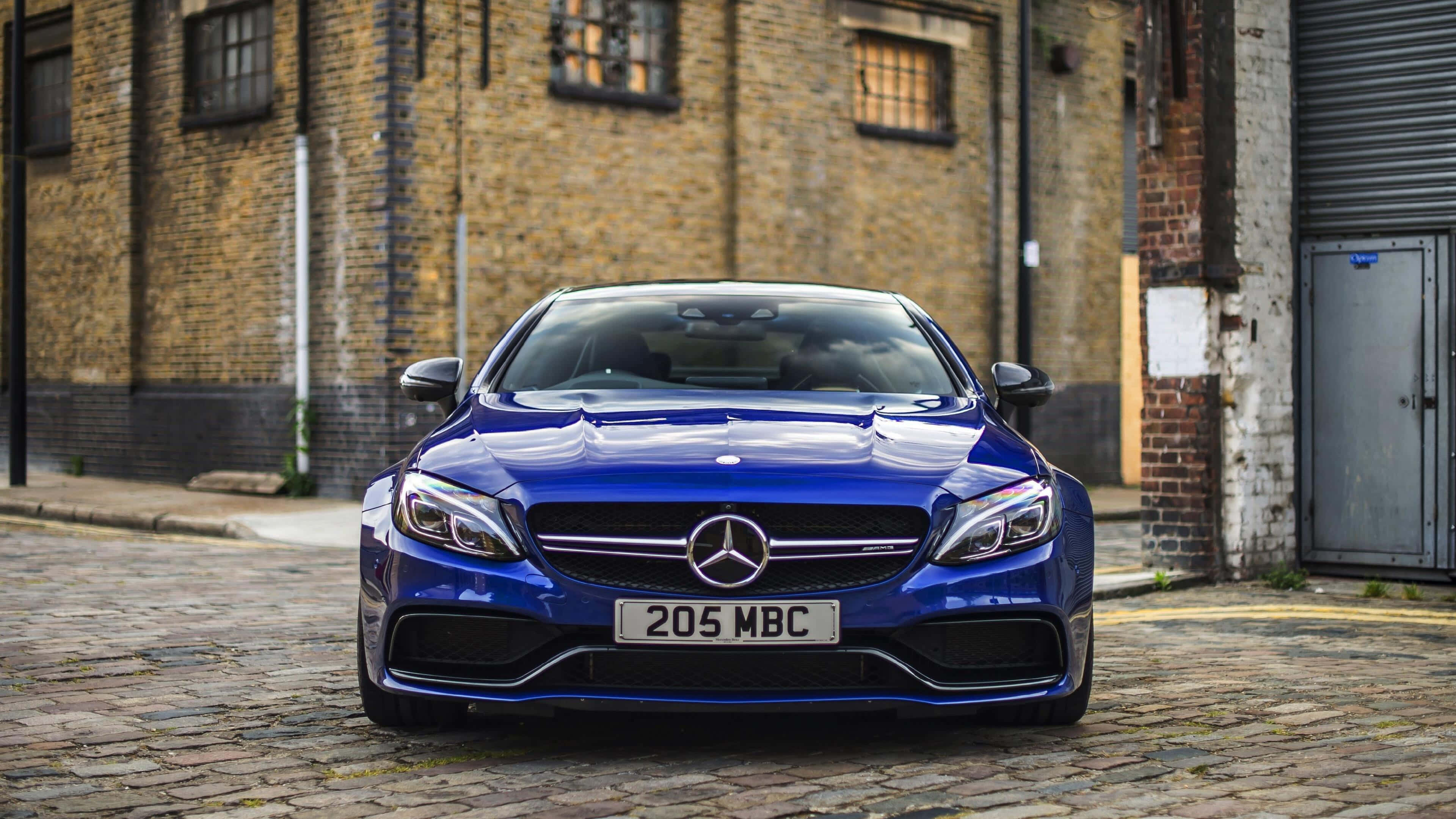 Mercedes 桌布 壁紙 — 一輛亮藍色的Mercedes-AMG C63停在鵝卵石街道上，前方是一棟風化的磚造建築。