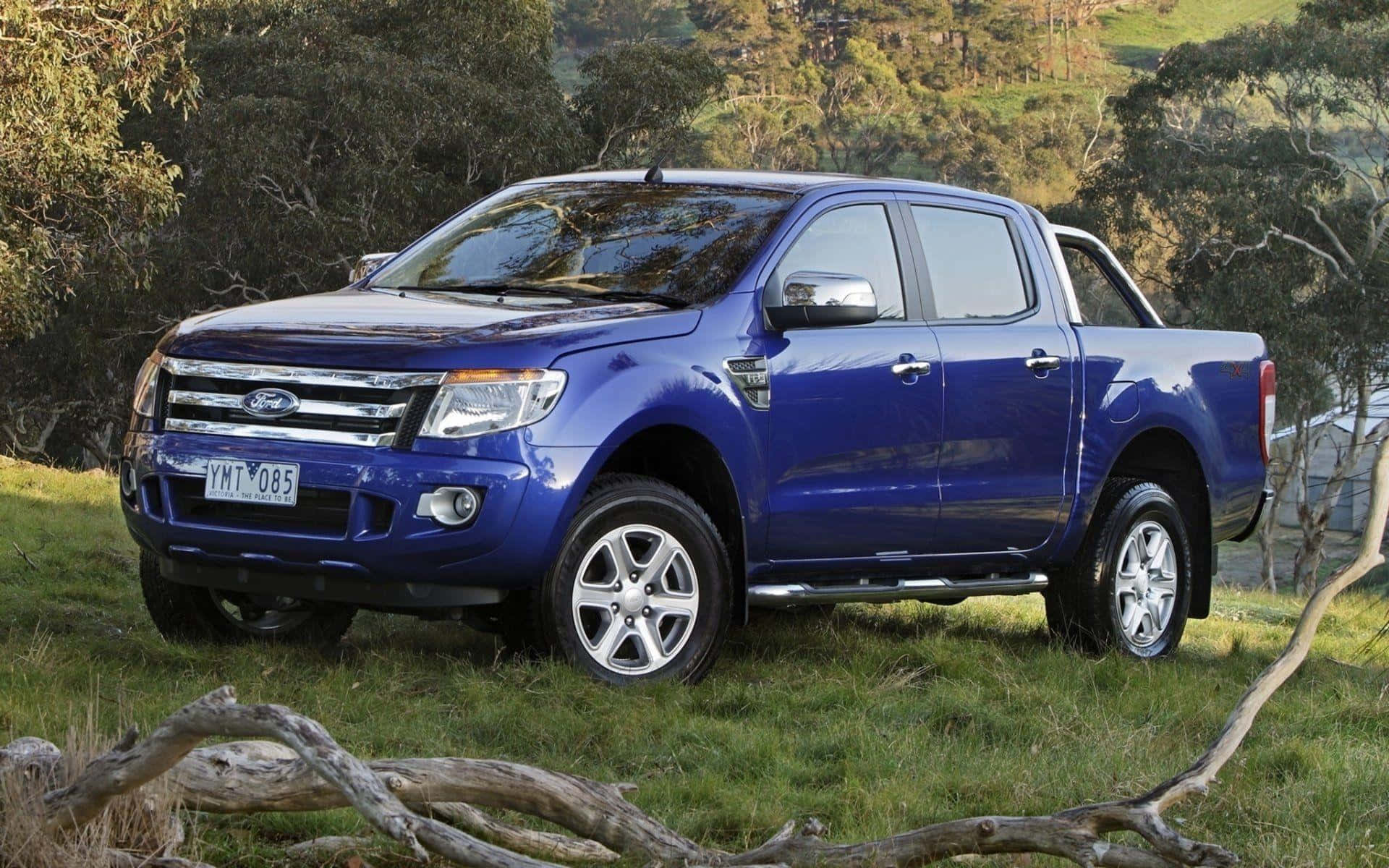 Ford Ranger 桌布 壁紙 — 一輛亮藍色的福特 Ranger 皮卡車停在草地上，前景有樹木和掉落的樹枝。