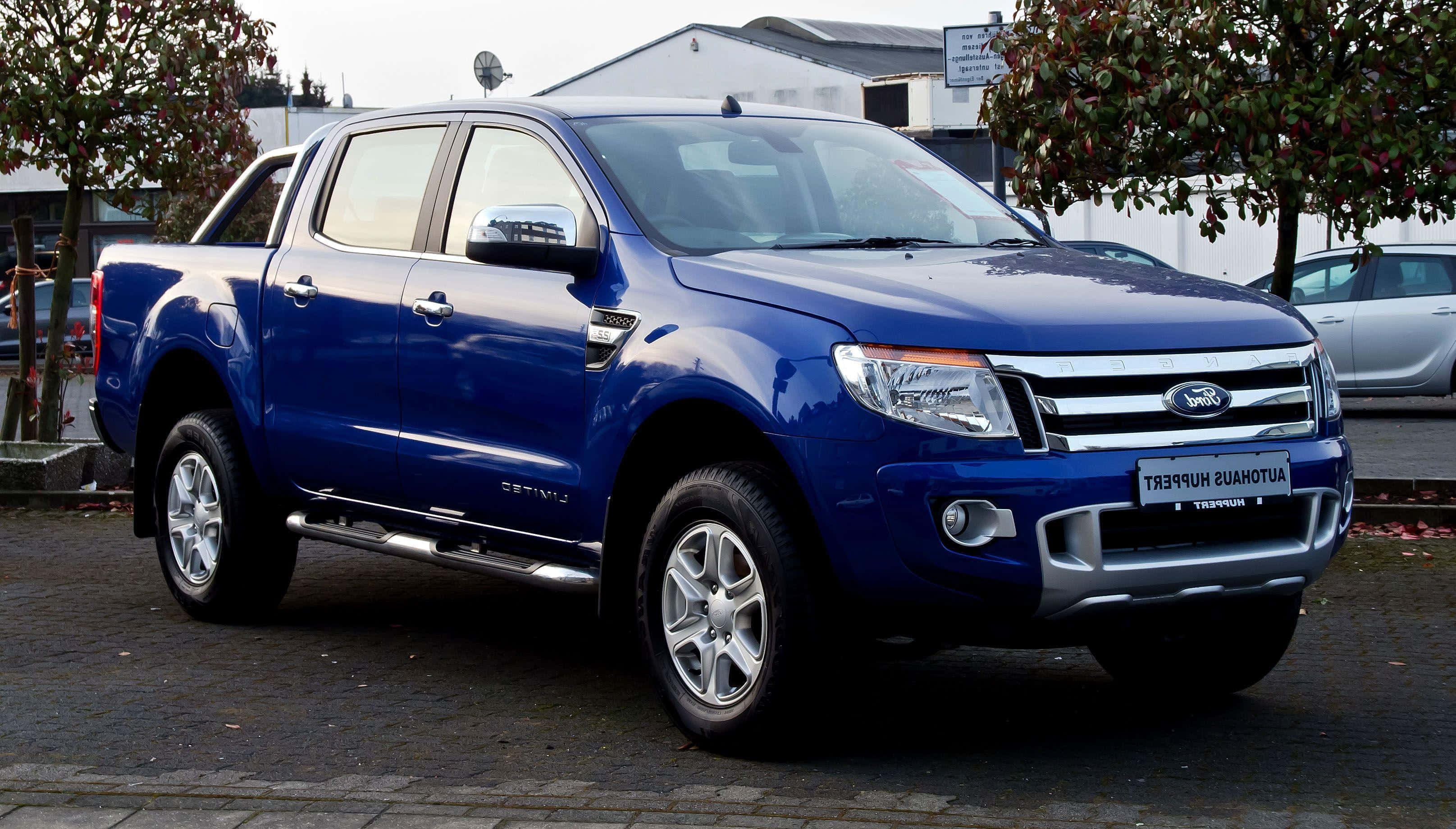 Ford Ranger 桌布 壁紙 — 一輛亮藍色福特Ranger pickup貨車停放在鋪砌的停車場，背景有樹木和建築物。