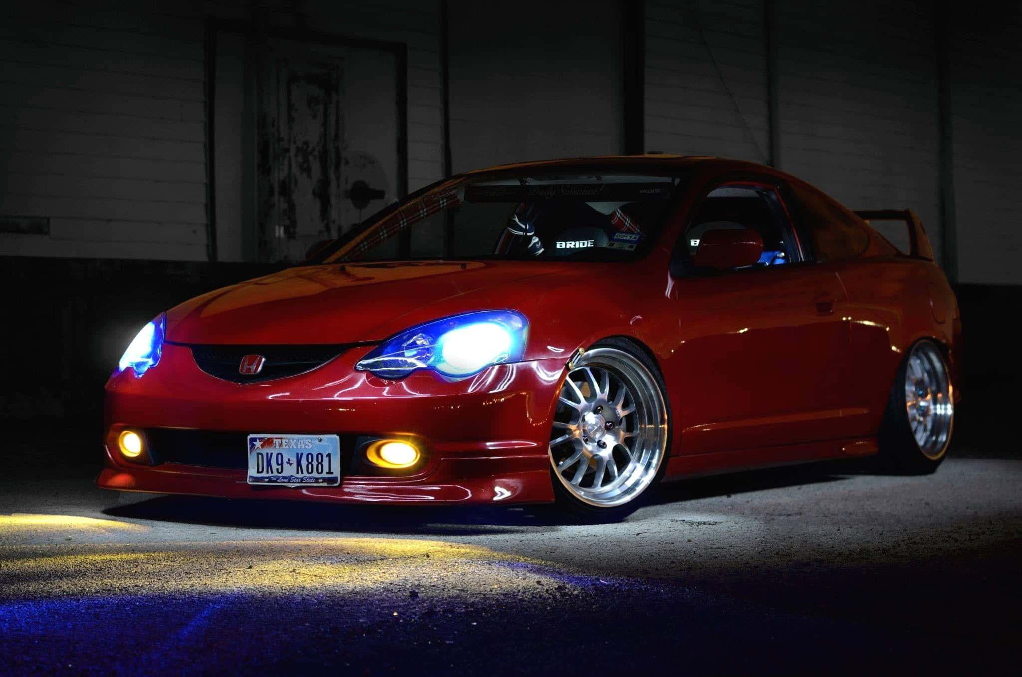 Rsx Type-s 桌布 壁紙 — 一輛亮面紅色改裝跑車，帶有發光藍色車頭燈，夜晚停放在燈光昏暗的車庫中。