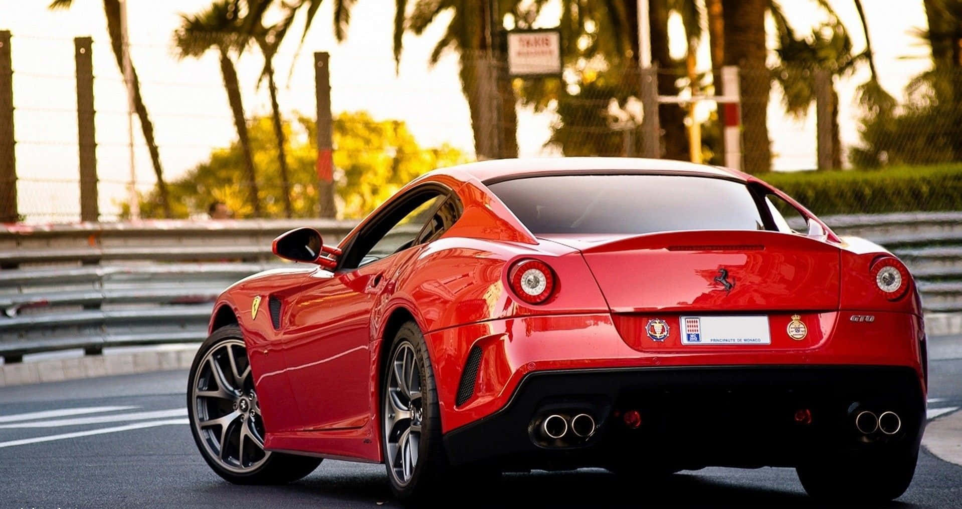 Ferrari 599 Gtb Fiorano 桌布 壁紙 — 一輛亮面紅色法拉利跑車停放在賽車場上，背景有棕櫚樹和日落燈光。