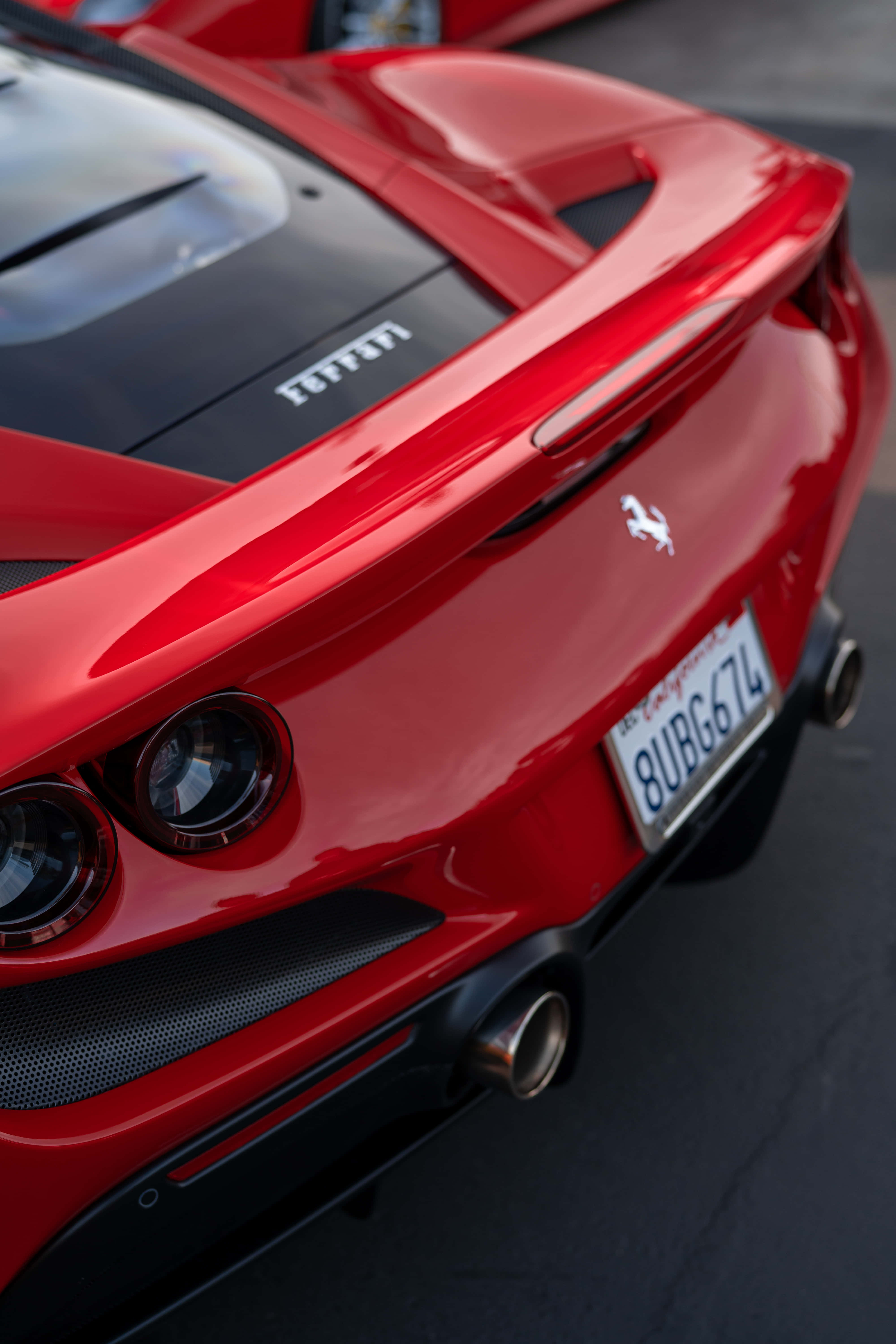 Ferrari iPhone 桌布 壁紙 — 一輛亮面紅色法拉利跑車的特寫，展示其流線型尾部設計和標誌性的躍馬標誌。