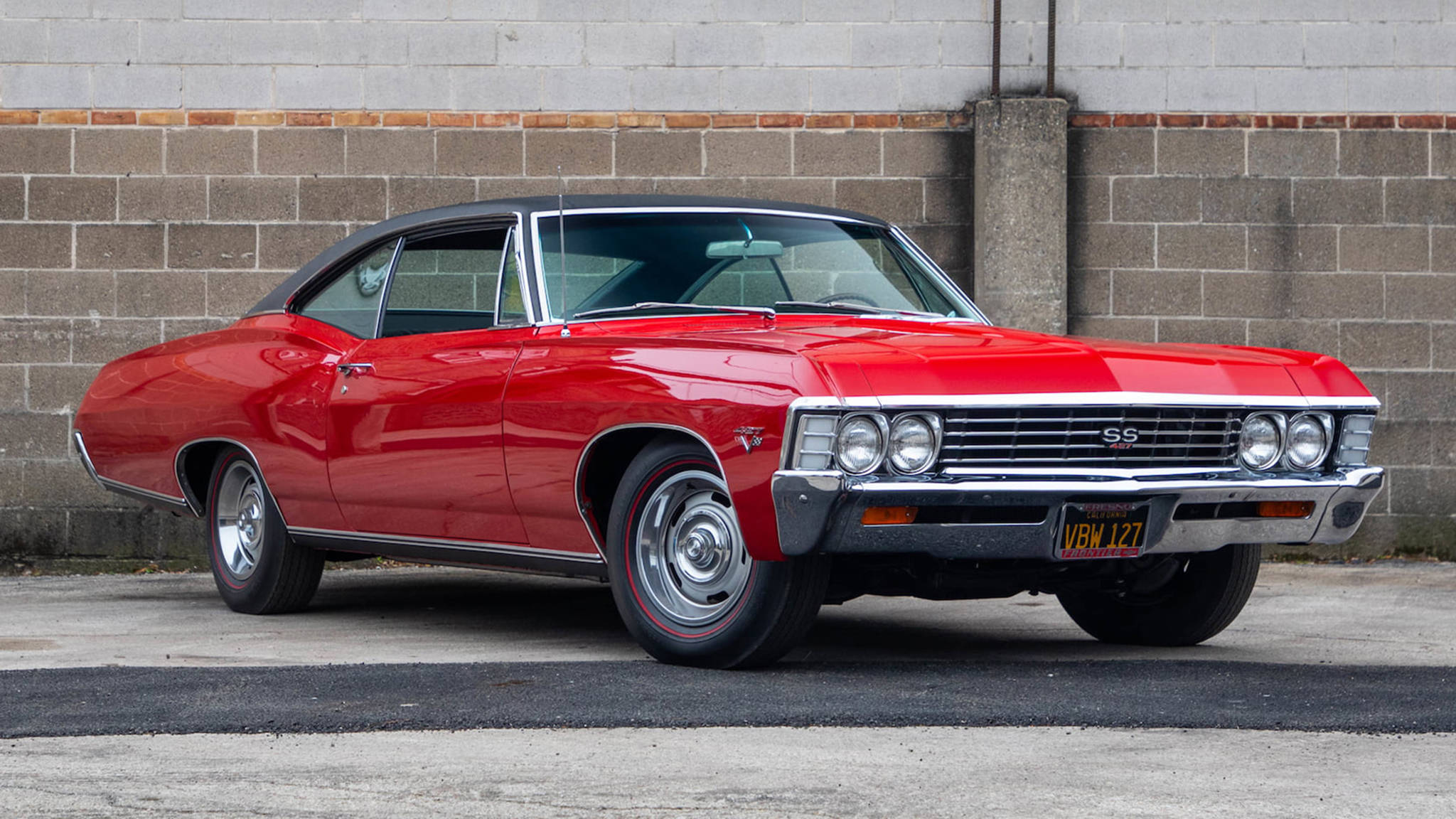 chevrolet impala 1967 桌布 壁紙 — 一輛亮面紅色經典雪佛蘭SS肌肉車停放在灰色磚牆旁的柏油路上。