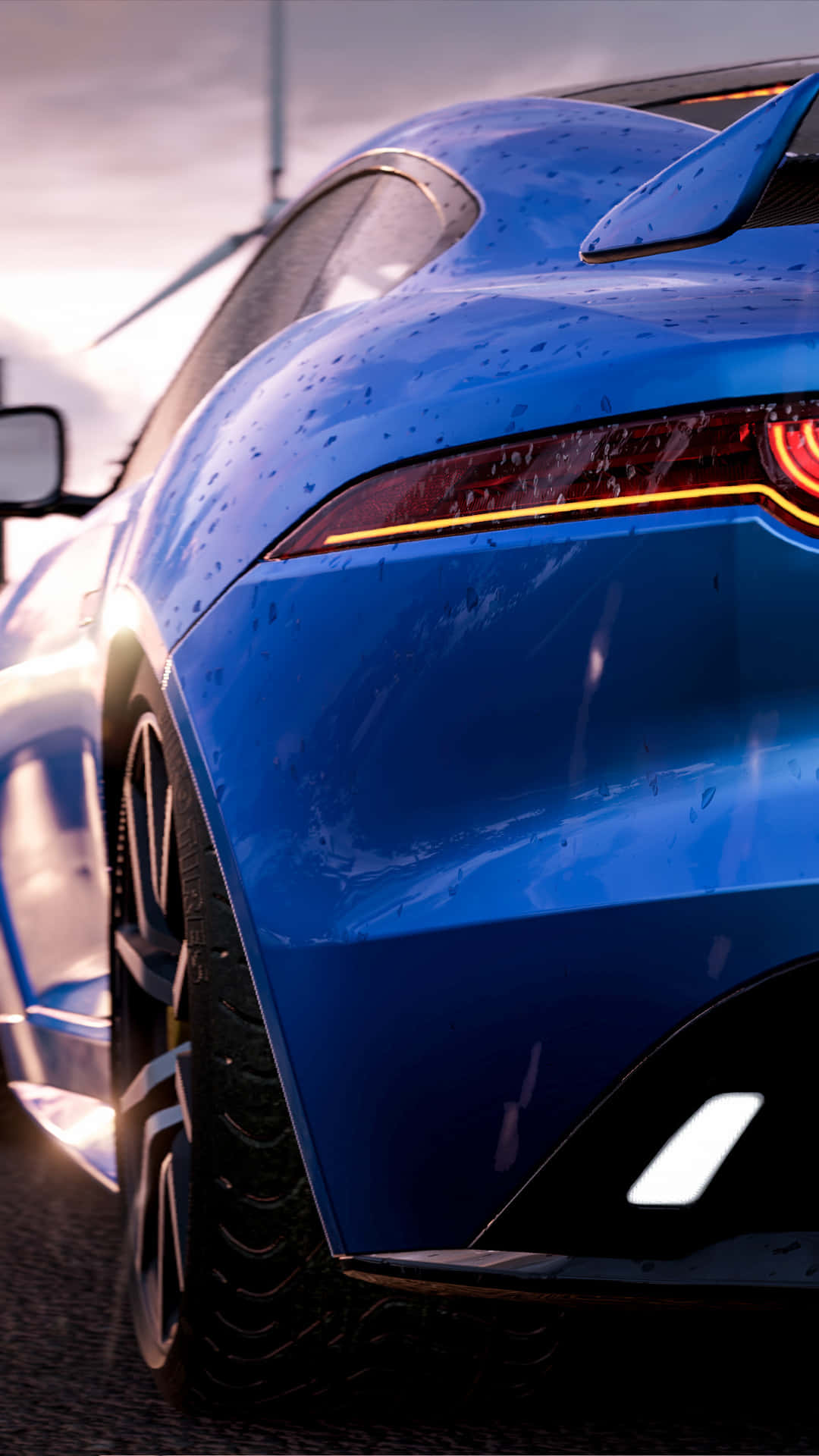 HD Project Cars 2 桌布 壁紙 — 一輛亮面藍色跑車帶著雨滴，在柔和的黎明天空下閃閃發光，背景有風力發電機。