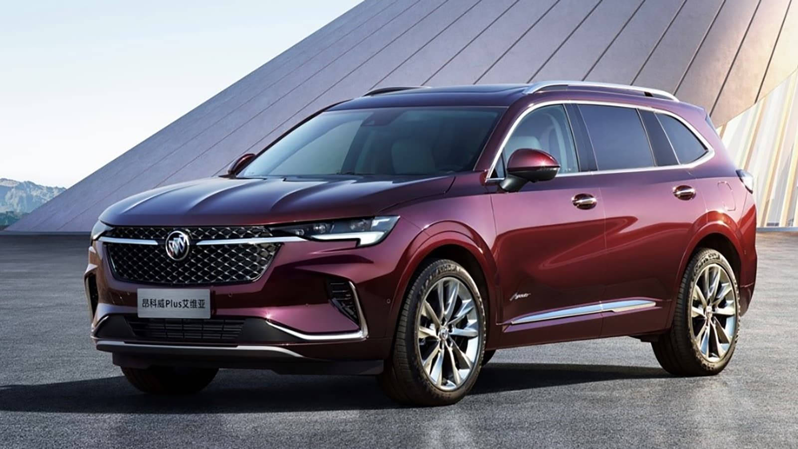 Buick 桌布 壁紙 — 一輛亮面酒紅色SUV停放在現代角形屋頂下，背景有山巒。