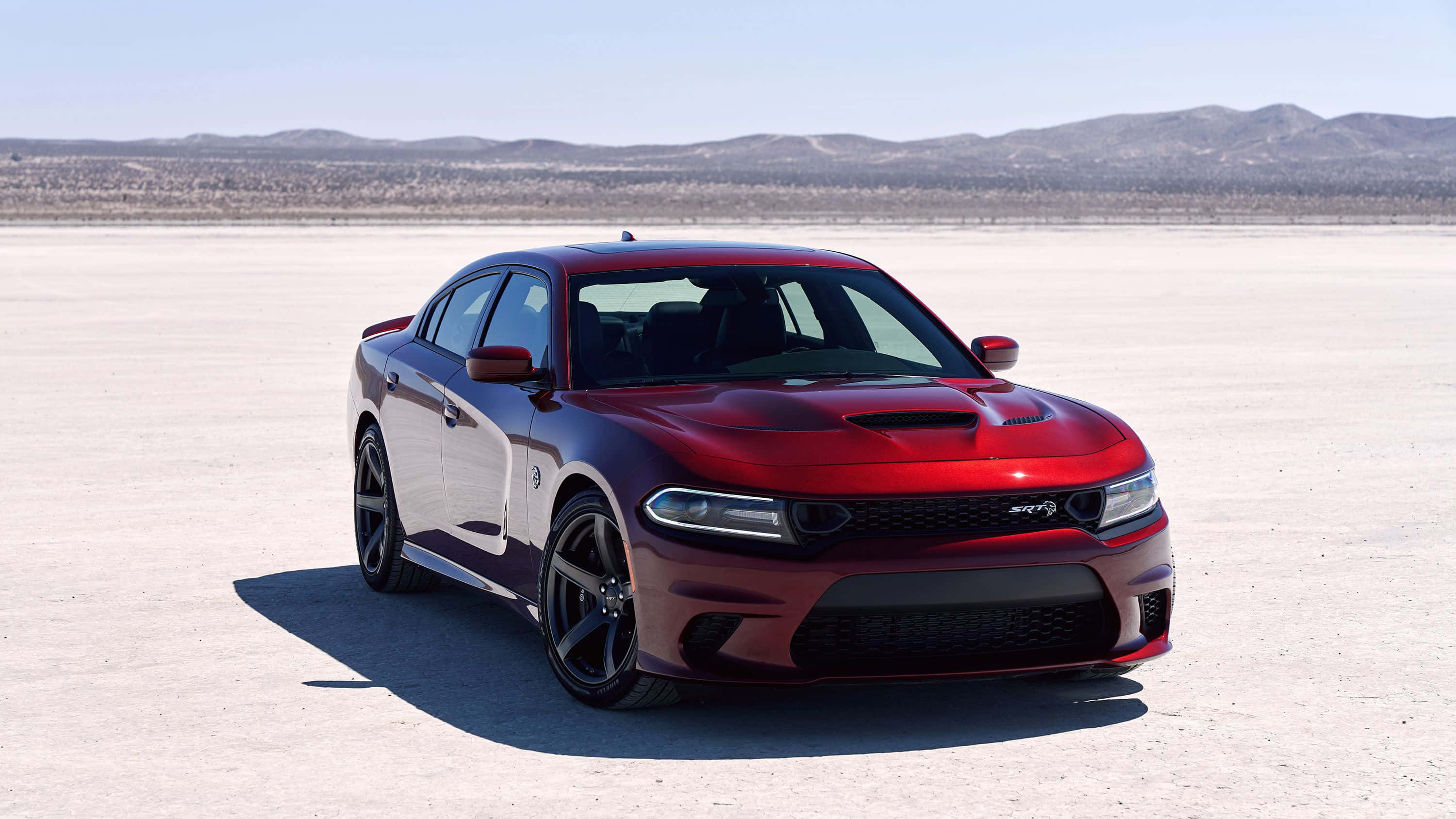 Dodge Charger 桌布 壁紙 — 一輛亮麗的紅色 Dodge Charger SRT Hellcat 停泊在廣闊的沙漠鹽灘上，遠方有山脈，天空清澈湛藍。