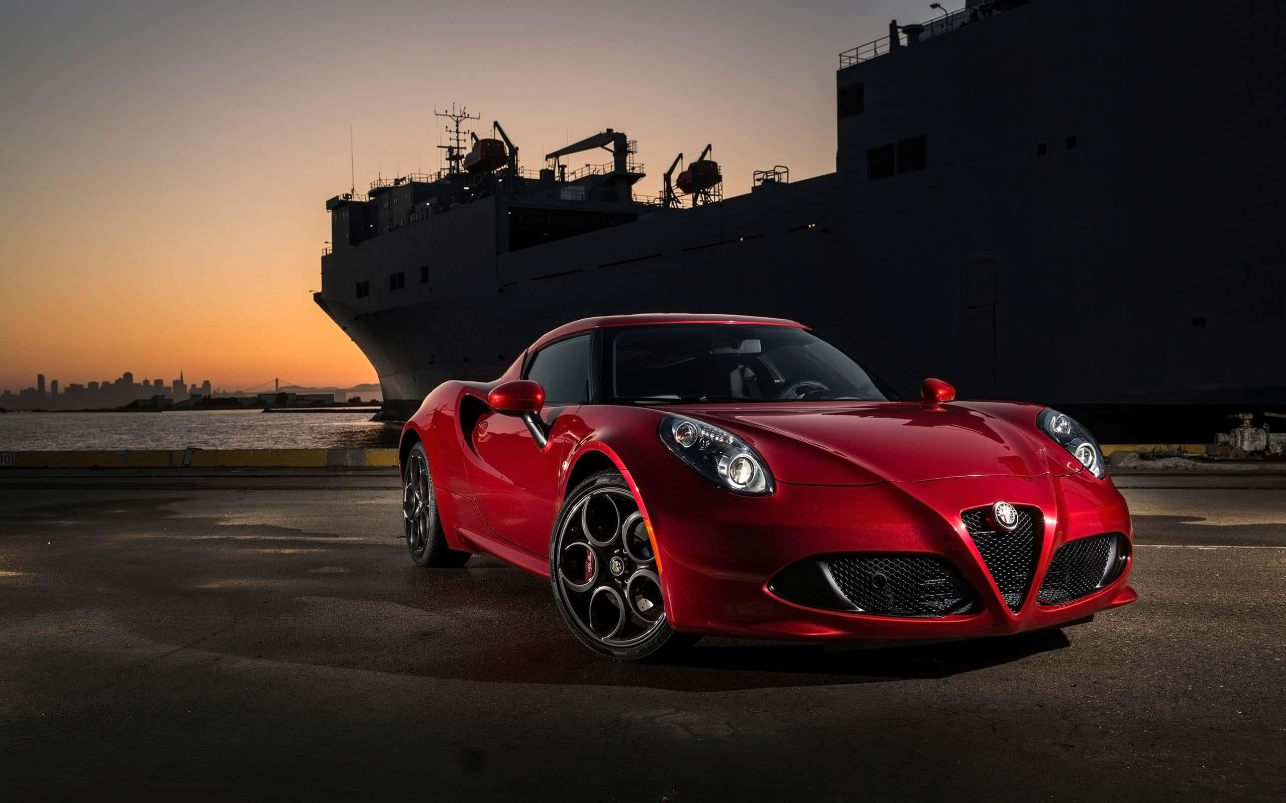 Alfa Romeo 4c 桌布 壁紙 — 一輛亮麗的紅色愛快羅密歐跑車在日落時分於港口一艘大型貨船旁閃耀。