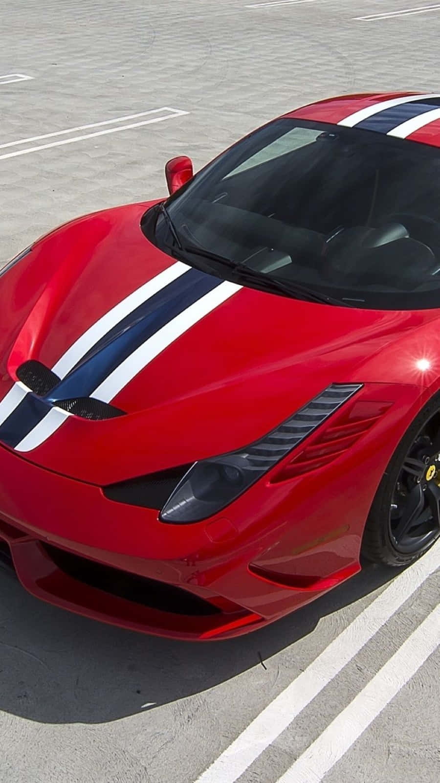 Ferrari 458 Speciale 桌布 壁紙 — 一輛亮麗的紅色法拉利跑車，帶有醒目的藍白賽車條紋，停泊在陽光普照的混凝土停車場。