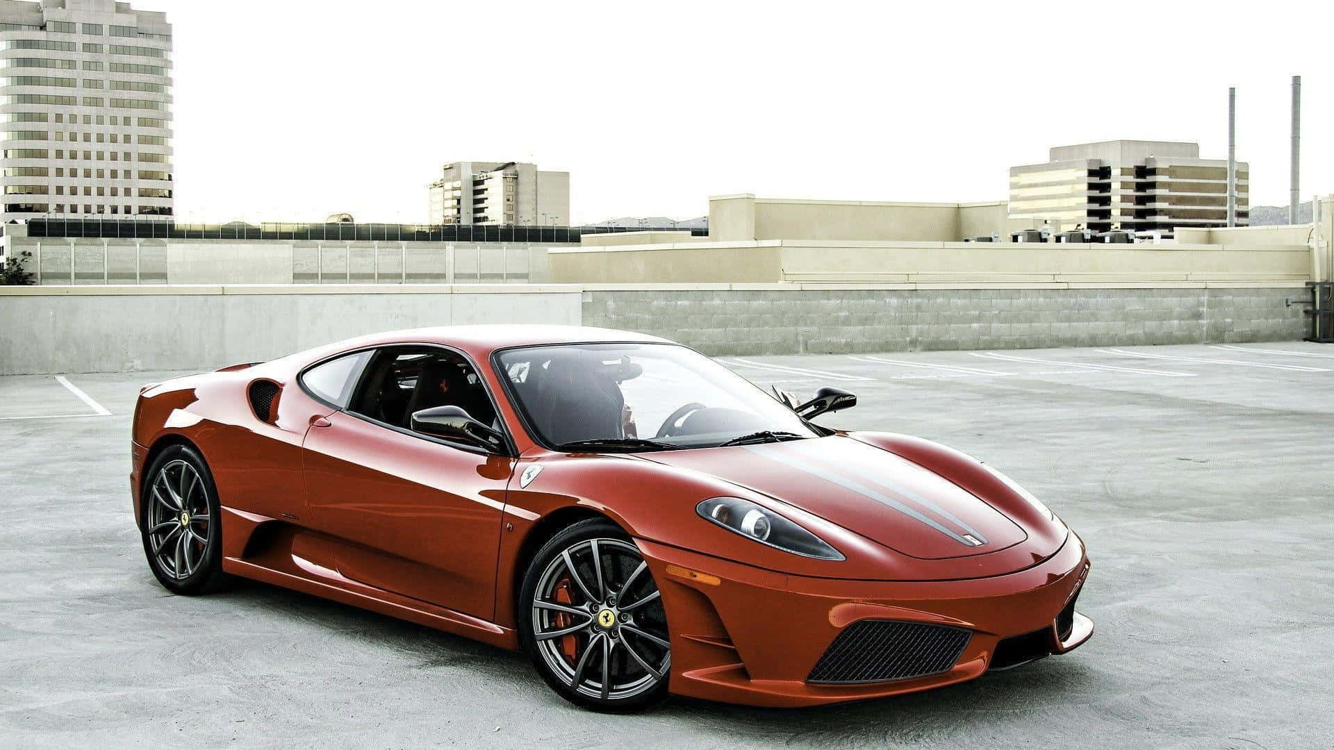 Ferrari F430 桌布 壁紙 — 一輛亮麗的紅色法拉利跑車停在混凝土屋頂上，背景是城市建築。