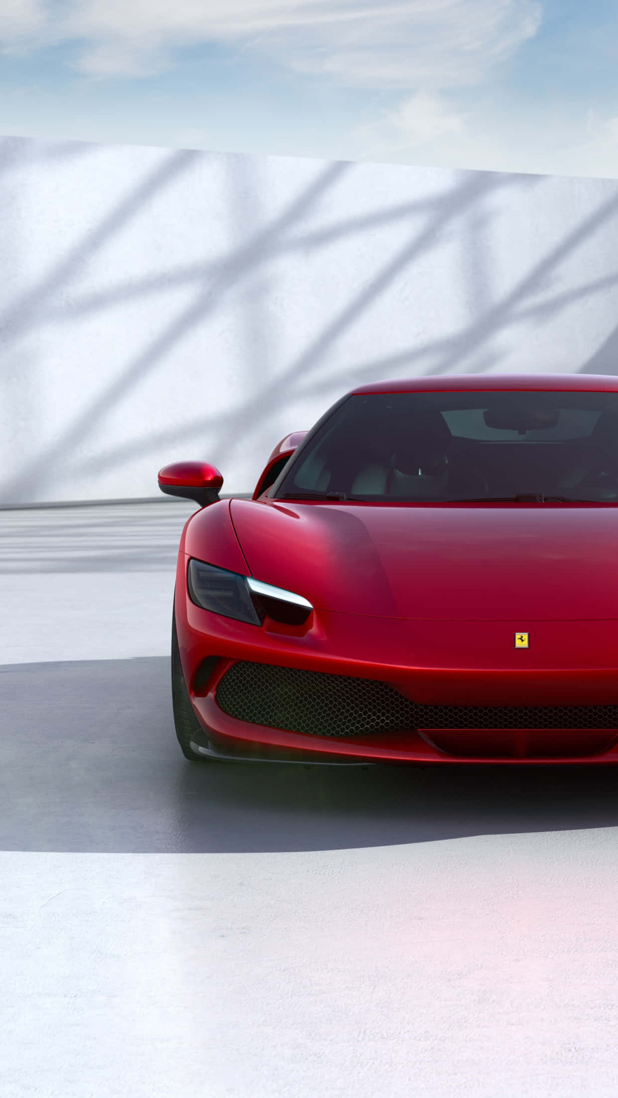Ferrari iPhone 桌布 壁紙 — 一輛亮麗的紅色法拉利跑車停放在極簡風格的混凝土地板上，幾何陰影投射在白色牆壁上，天空明亮。